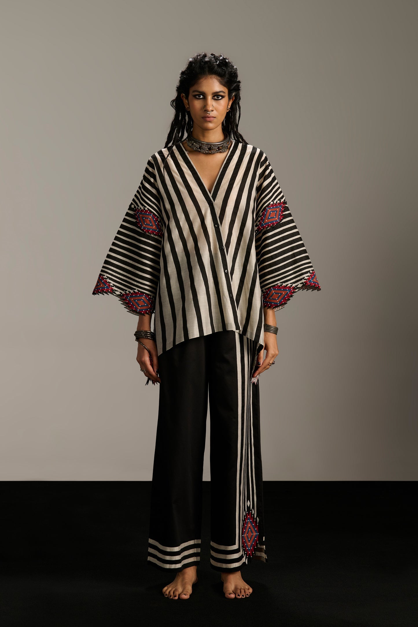 Woman wearing a black and white striped outfit with red accents against a plain background