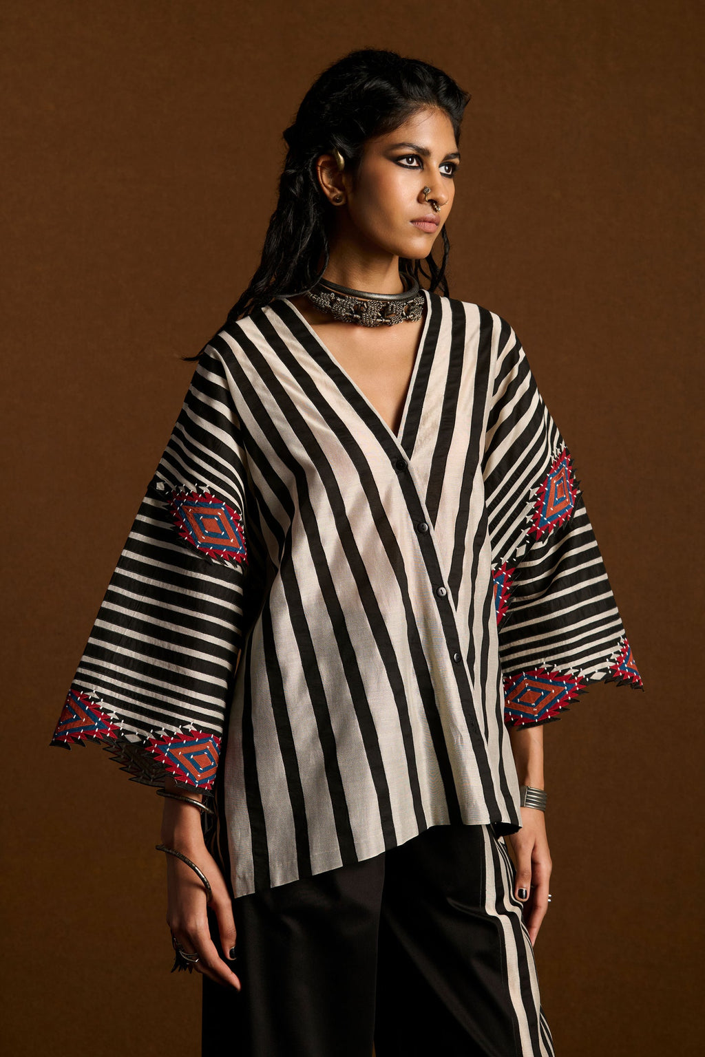 Woman wearing a black and white striped top with colorful accents on a brown background