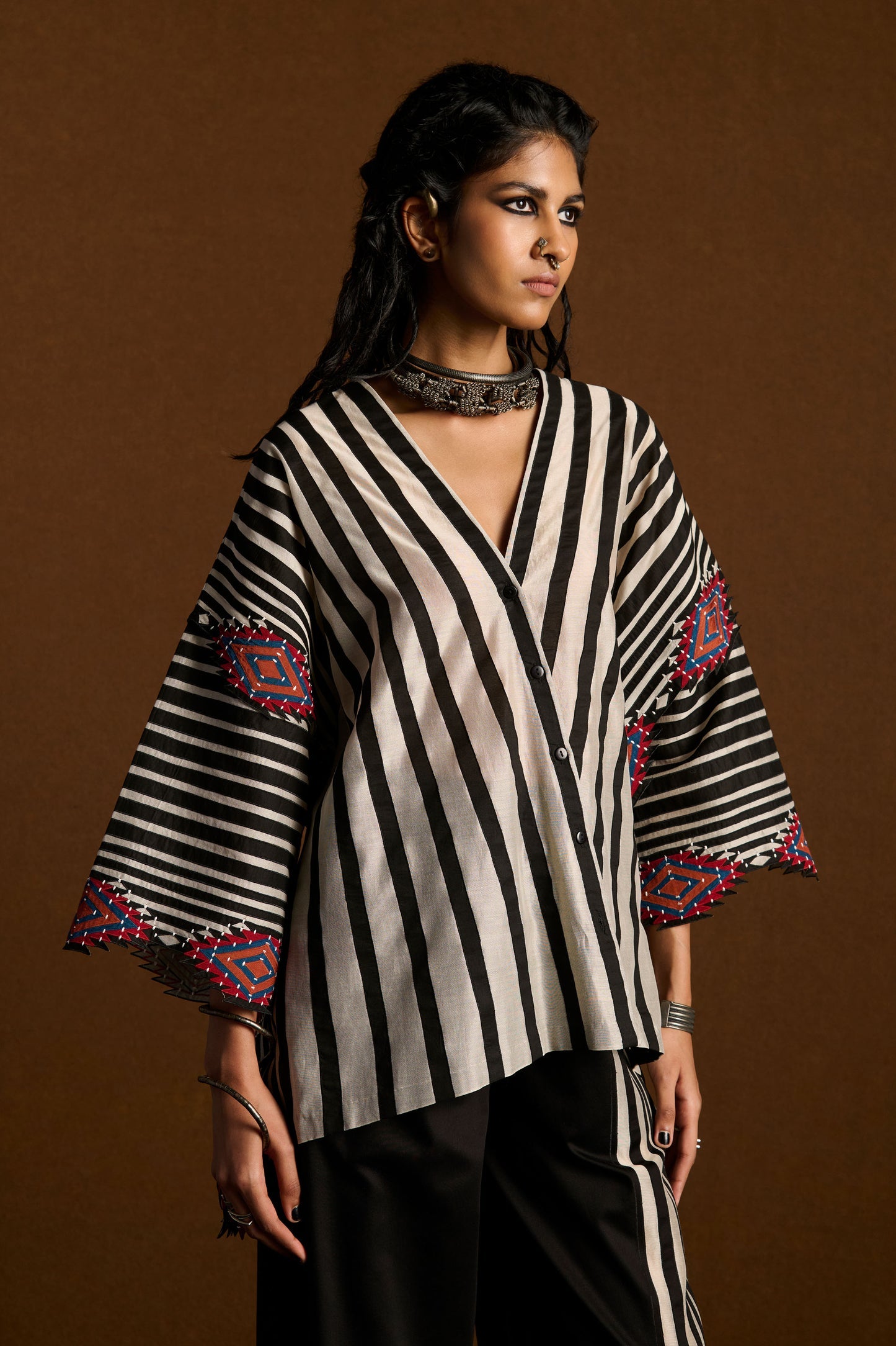 Woman wearing a black and white striped top with colorful accents on a brown background