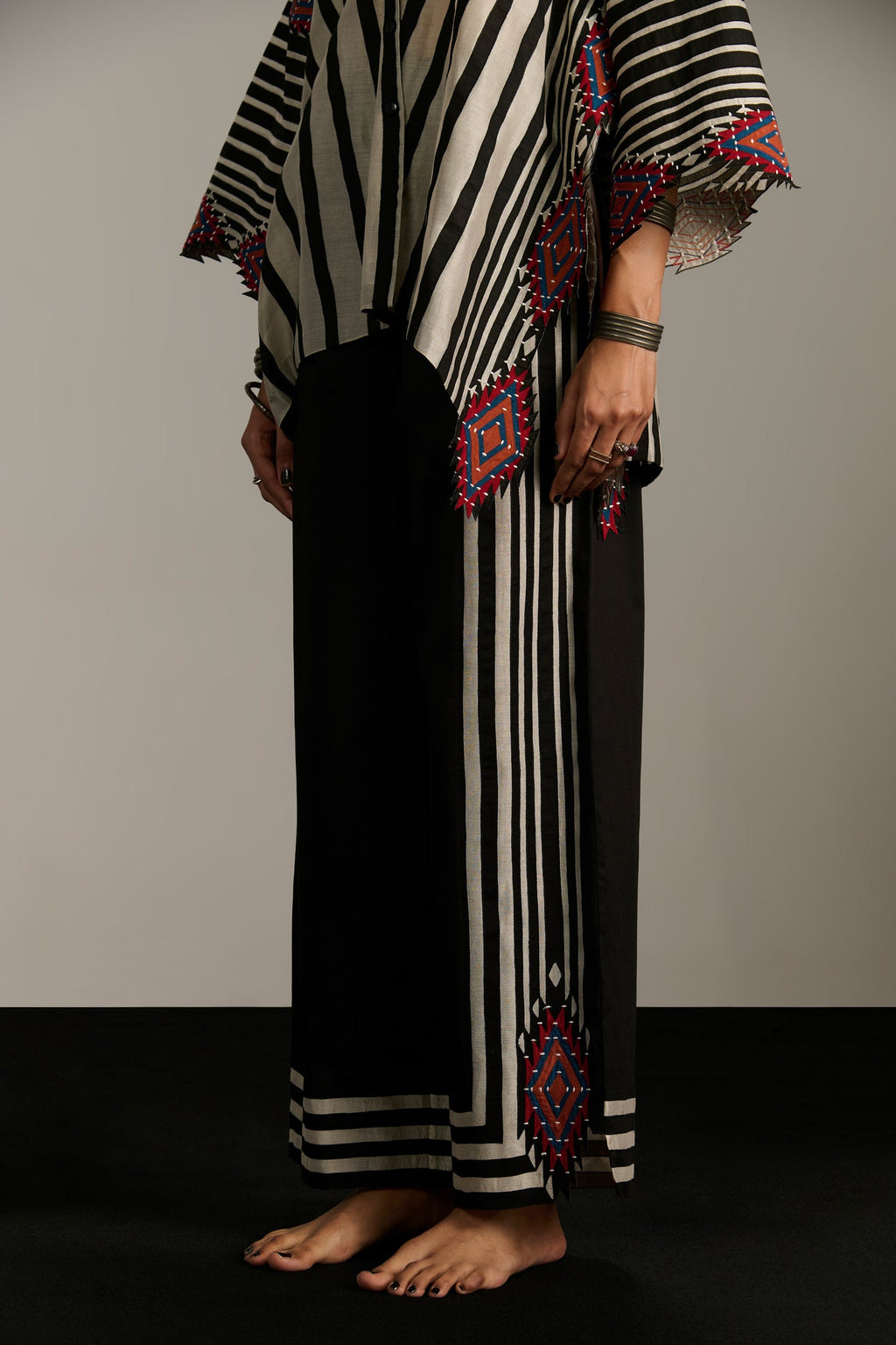 Person wearing a black and white striped outfit with decorative patterns on a plain background