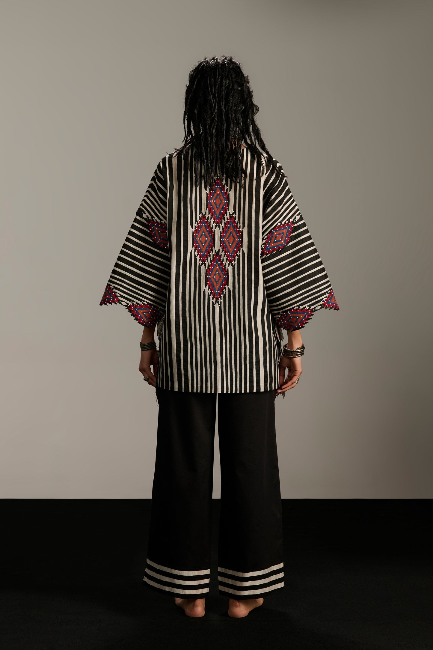 Person wearing a black and white patterned outfit with a plain background