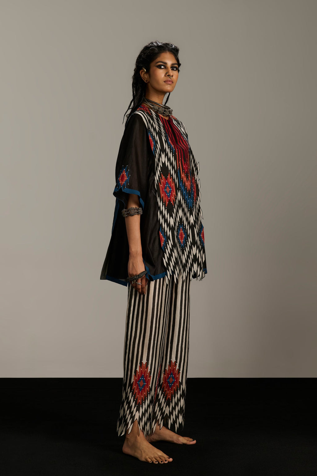 Woman wearing a traditional outfit with intricate patterns on a plain background