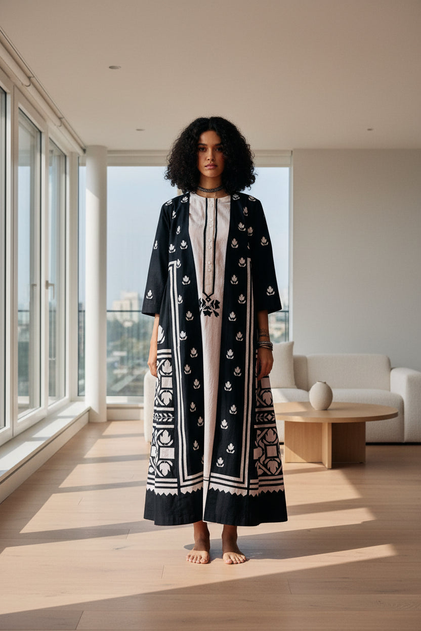 Woman wearing a black and white patterned dress on a red carpet with a black background