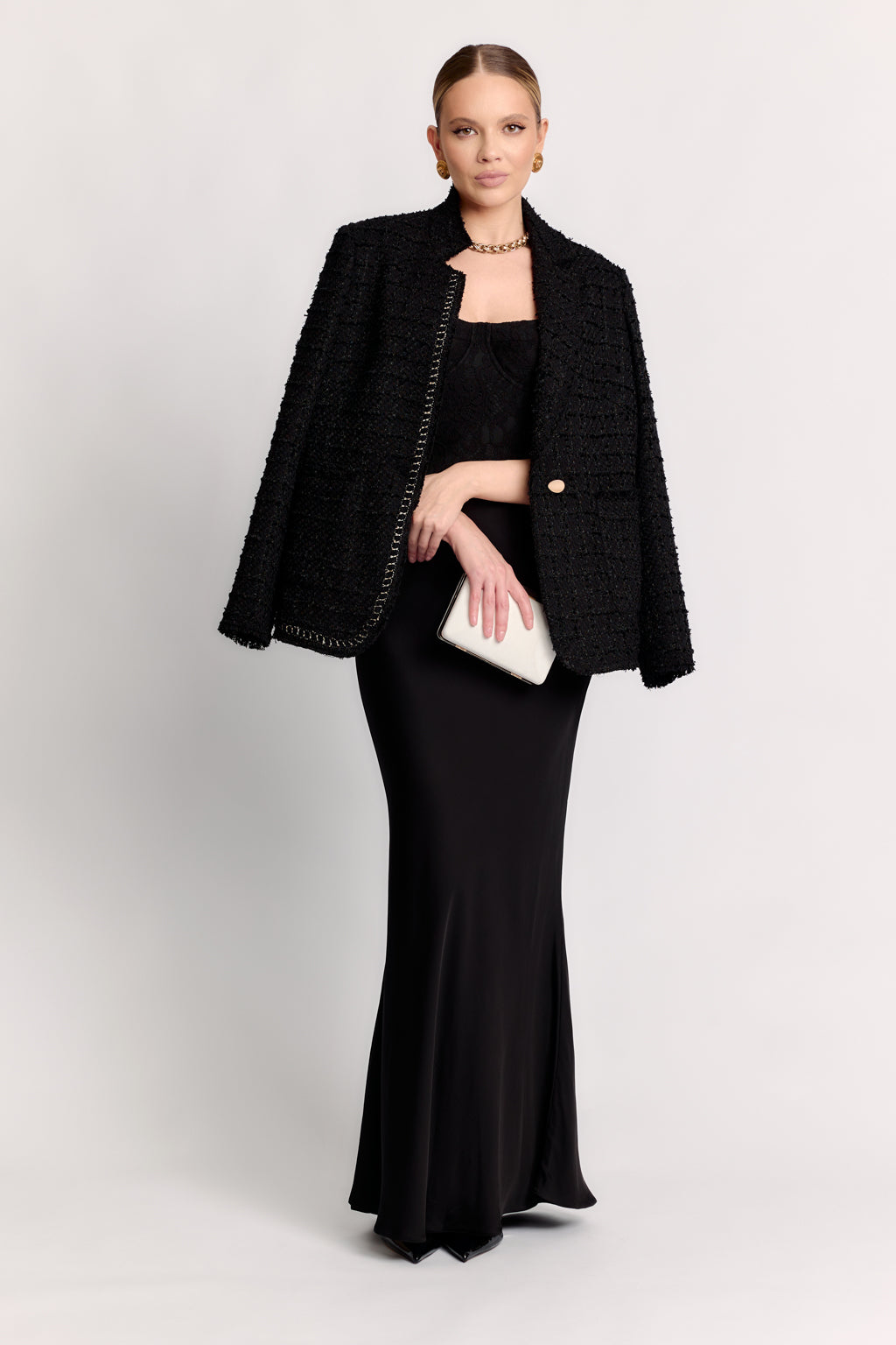 Woman wearing a black outfit with a jacket and clutch on a white background