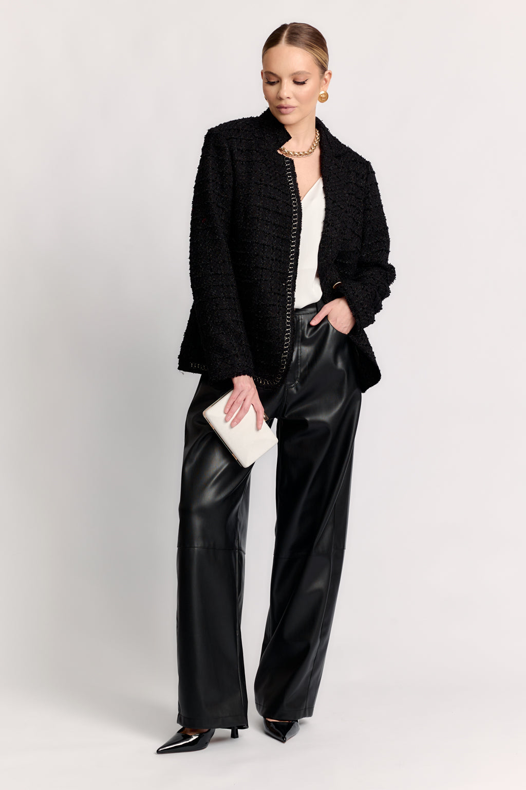 Woman wearing a black textured jacket and leather pants on a white background