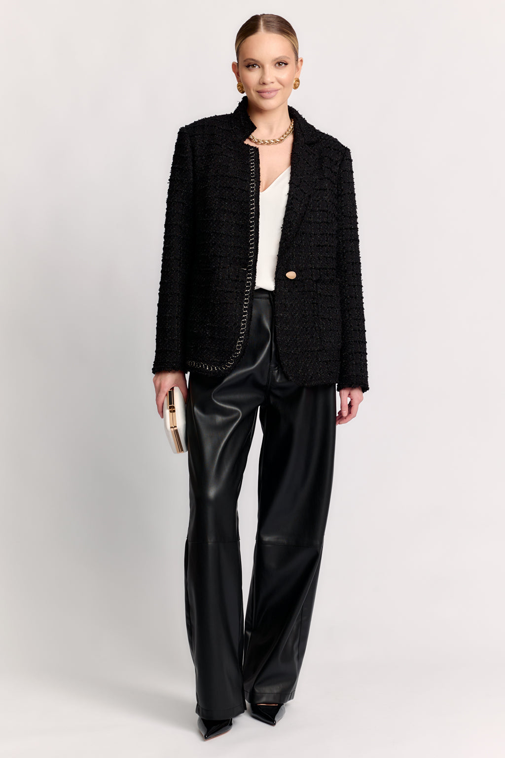 Woman wearing a black textured jacket and black pants on a white background