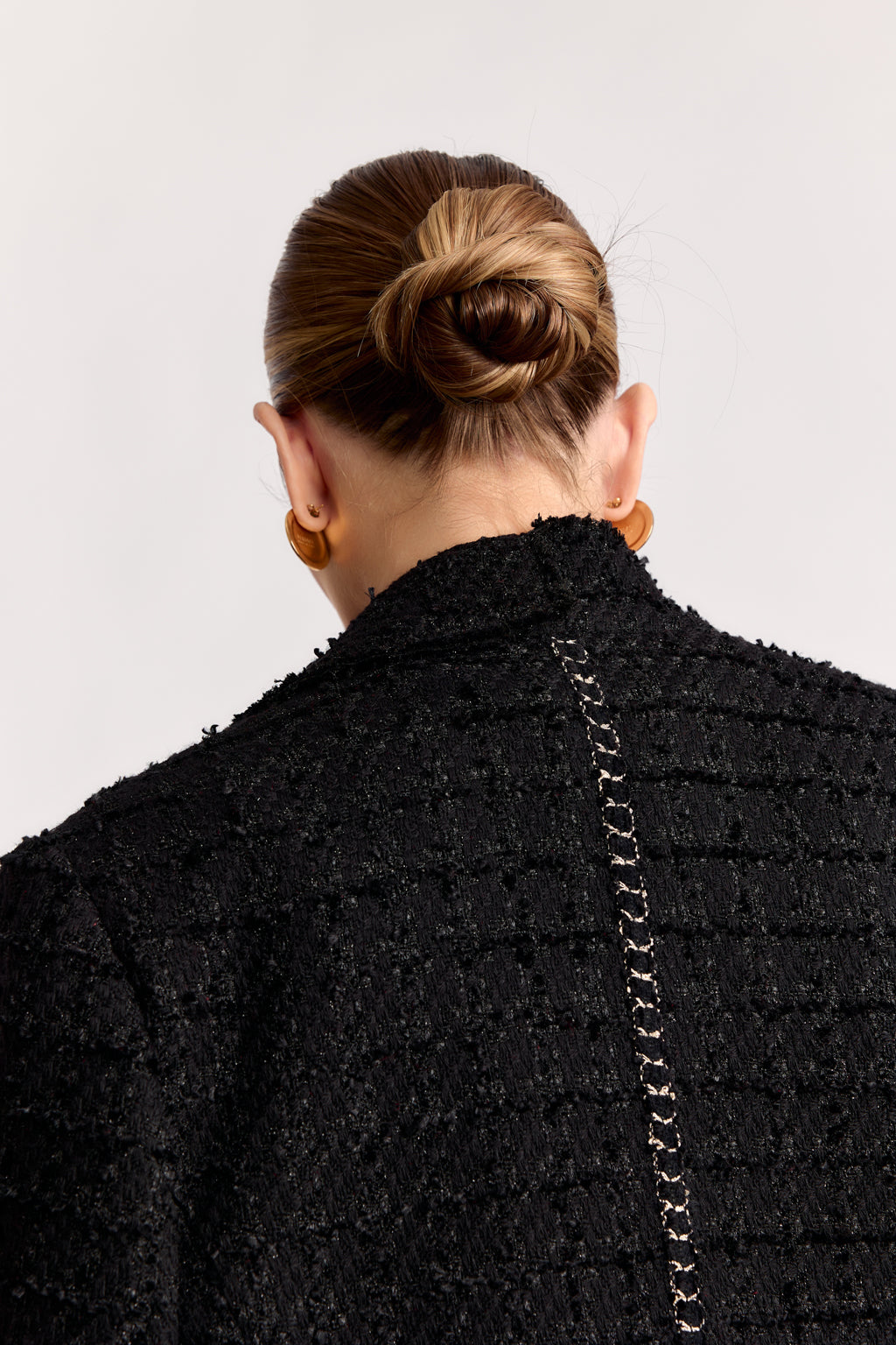 Person wearing a black textured coat with a plain background