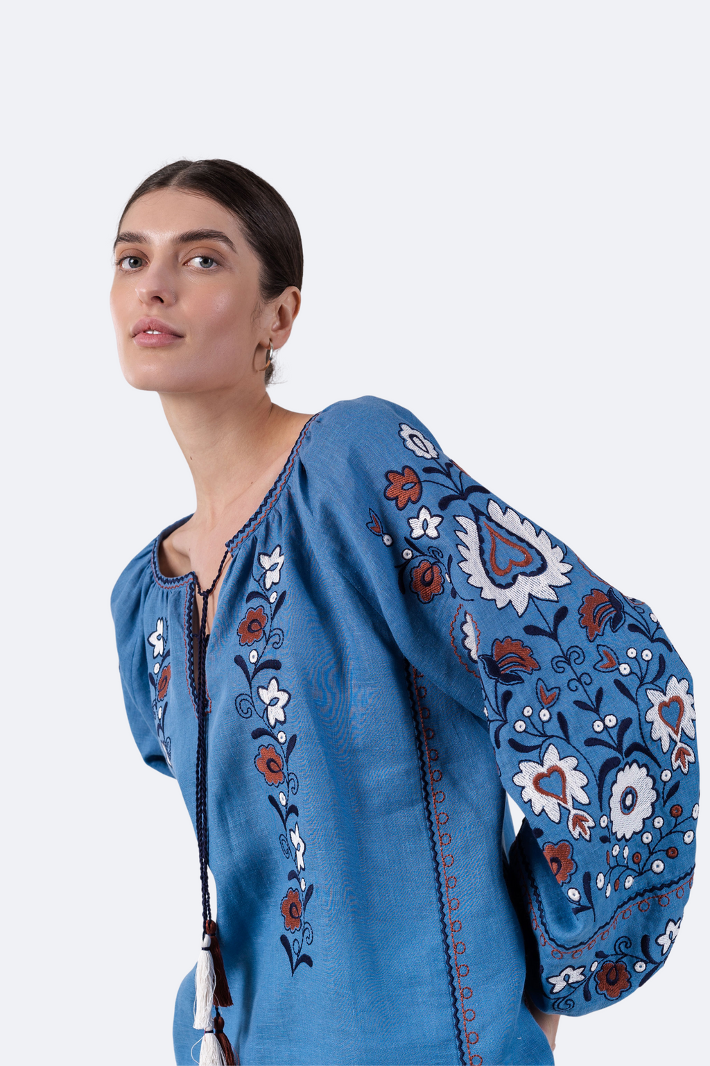 Woman wearing a blue embroidered blouse against a white background