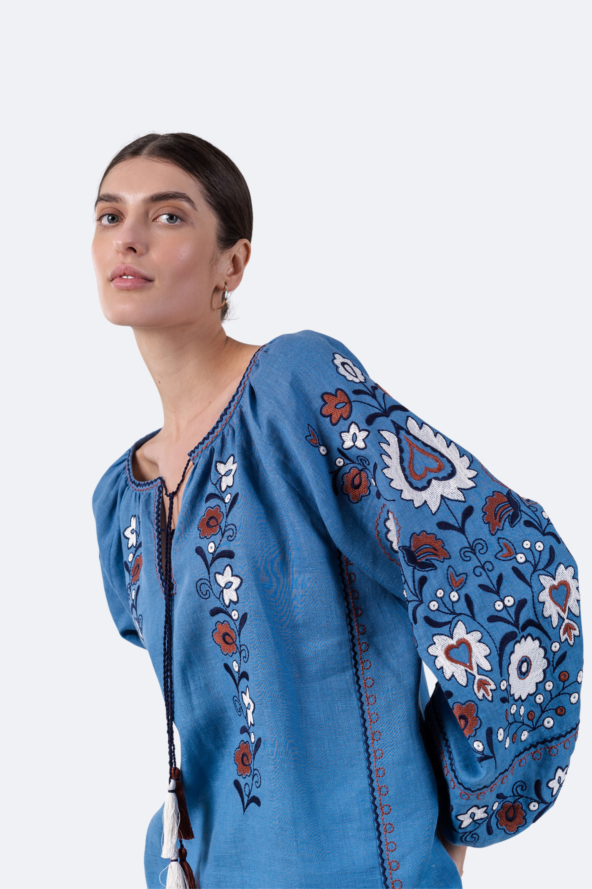 Woman wearing a blue embroidered blouse against a white background