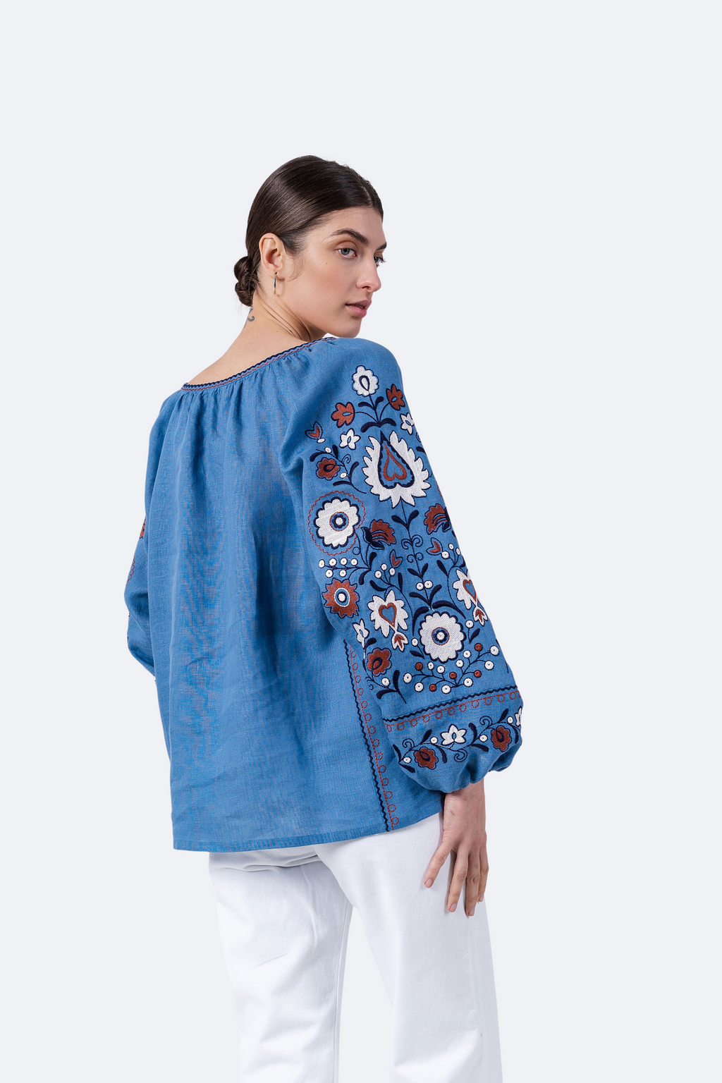 Woman wearing a blue blouse with floral embroidery on a white background