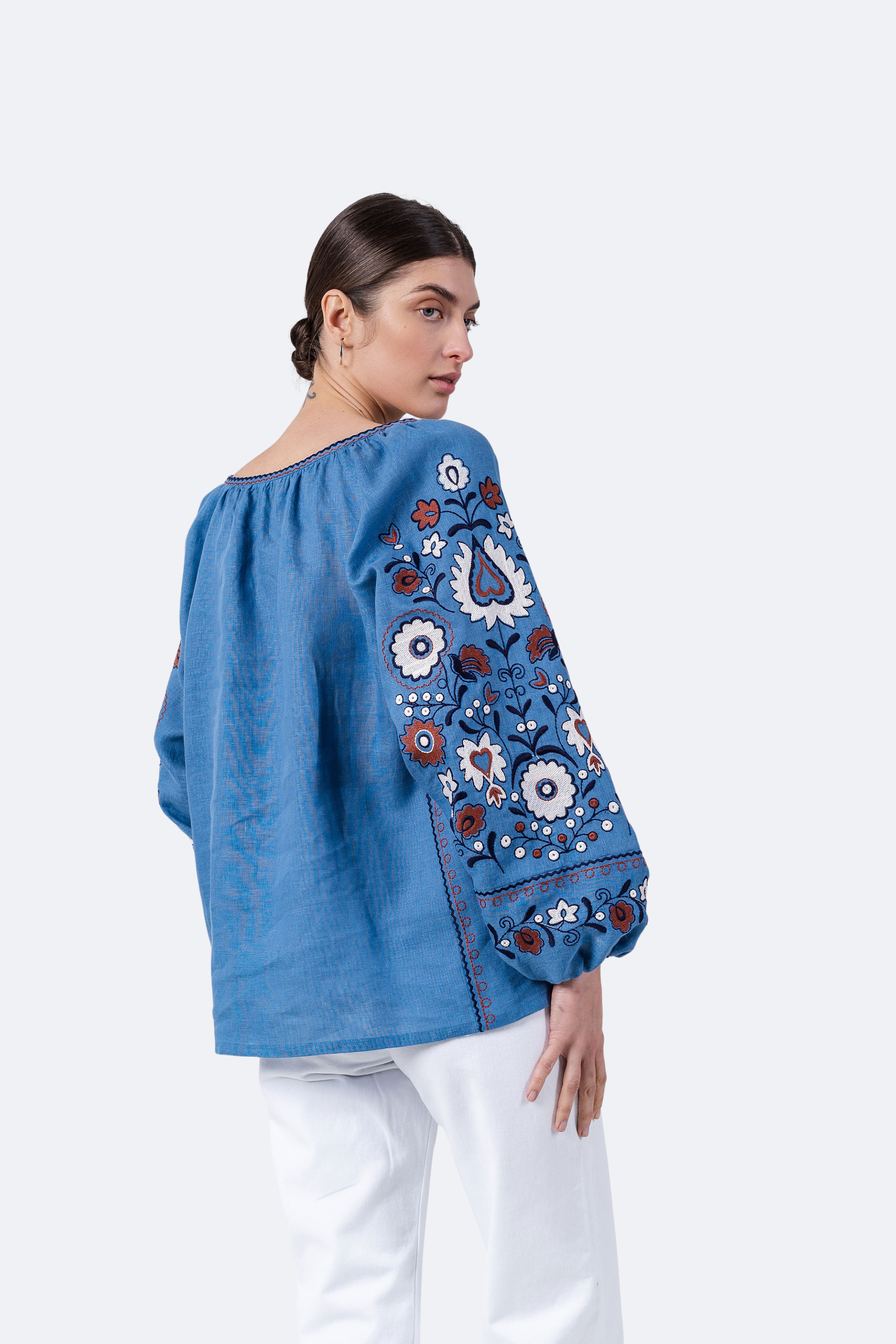 Woman wearing a blue blouse with floral embroidery on a white background