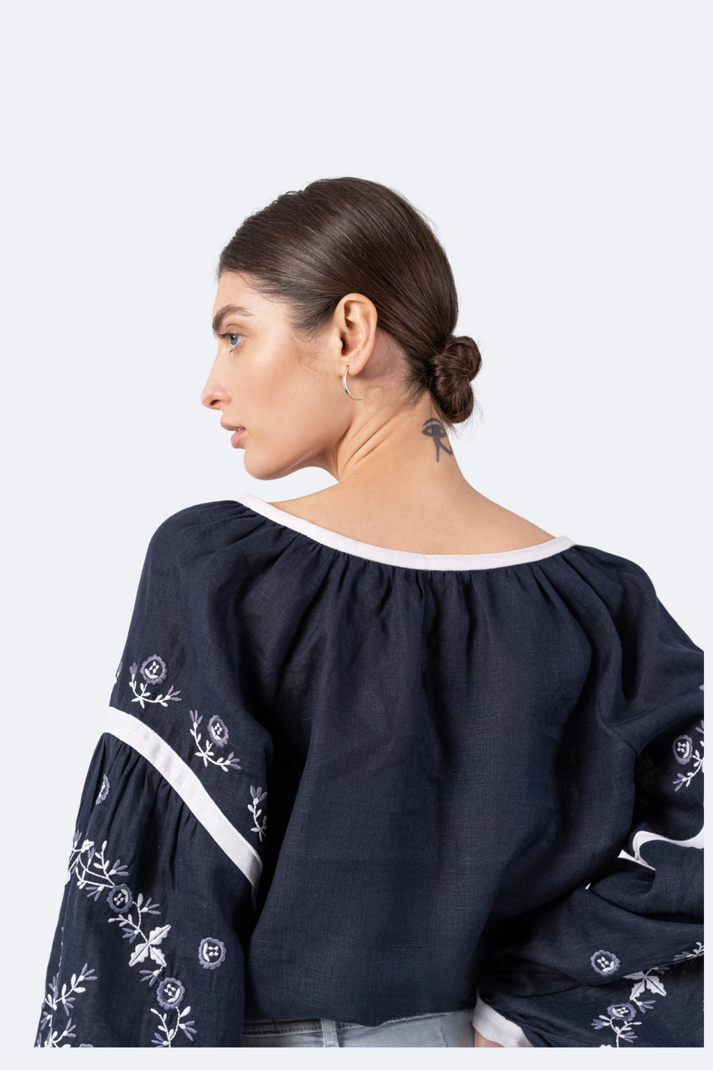 Woman wearing a navy blue embroidered blouse on a white background