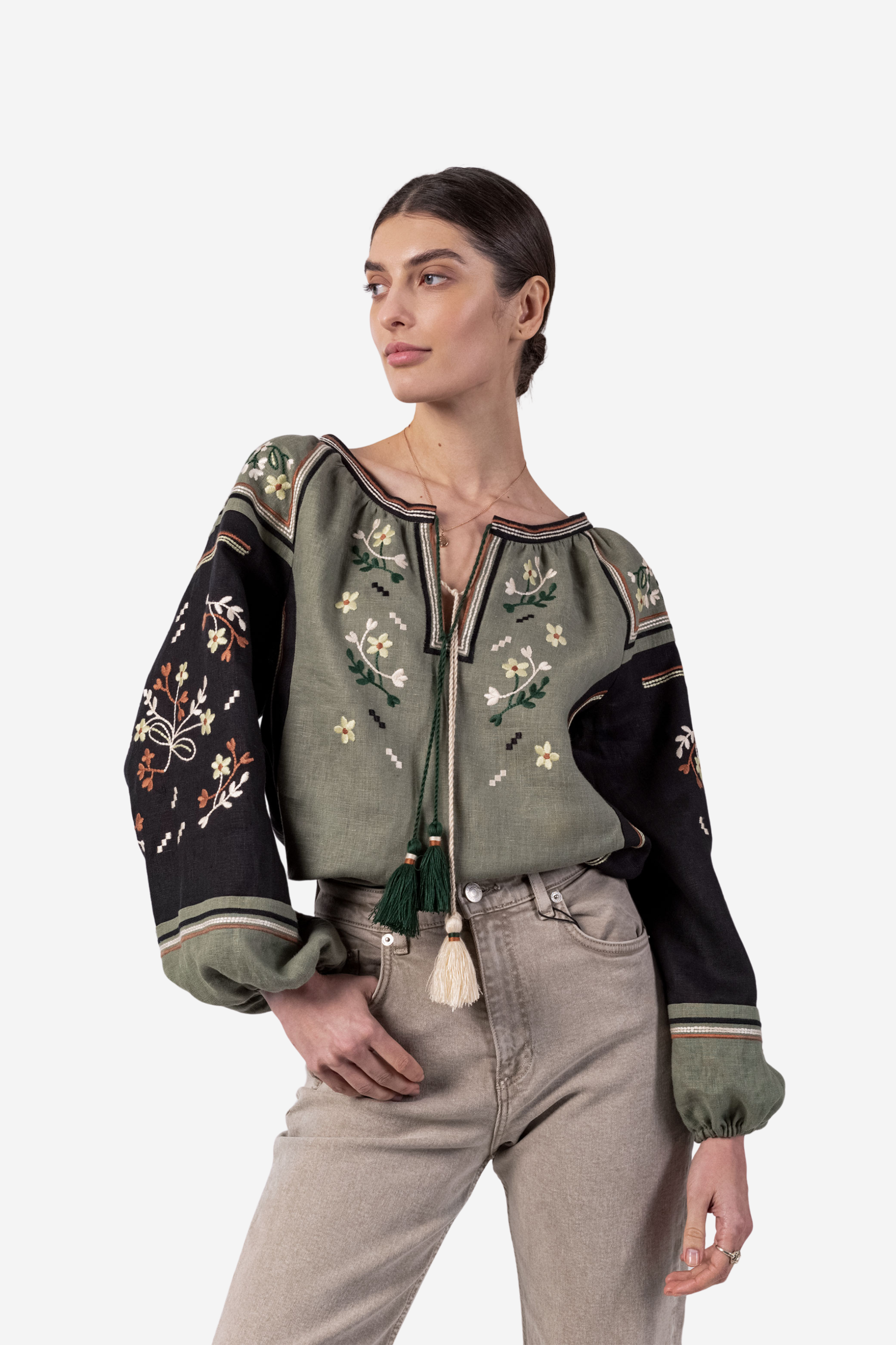 Woman wearing a green and black embroidered jacket on a white background
