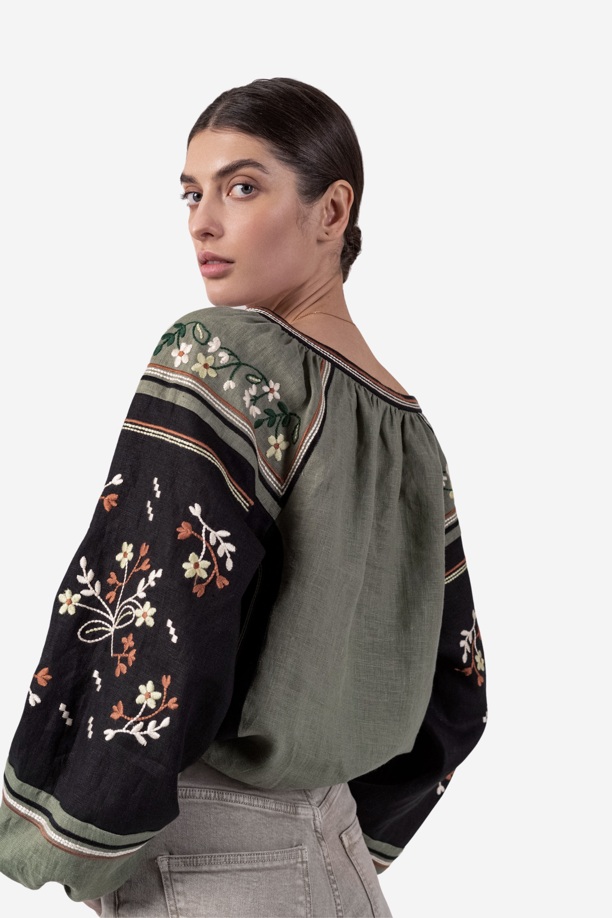 Woman wearing a green blouse with floral embroidery on a white background