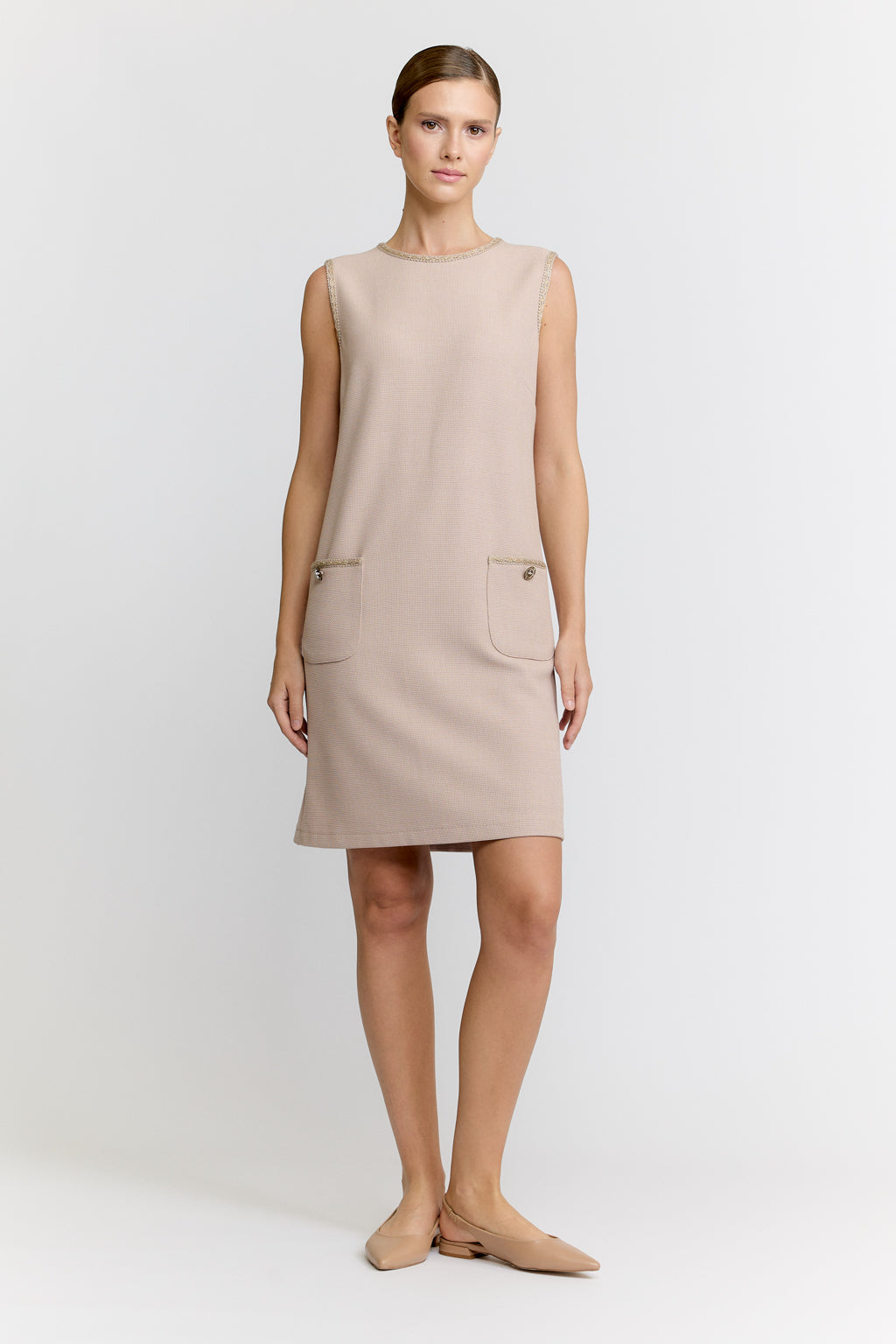 Woman wearing a beige sleeveless dress on a white background