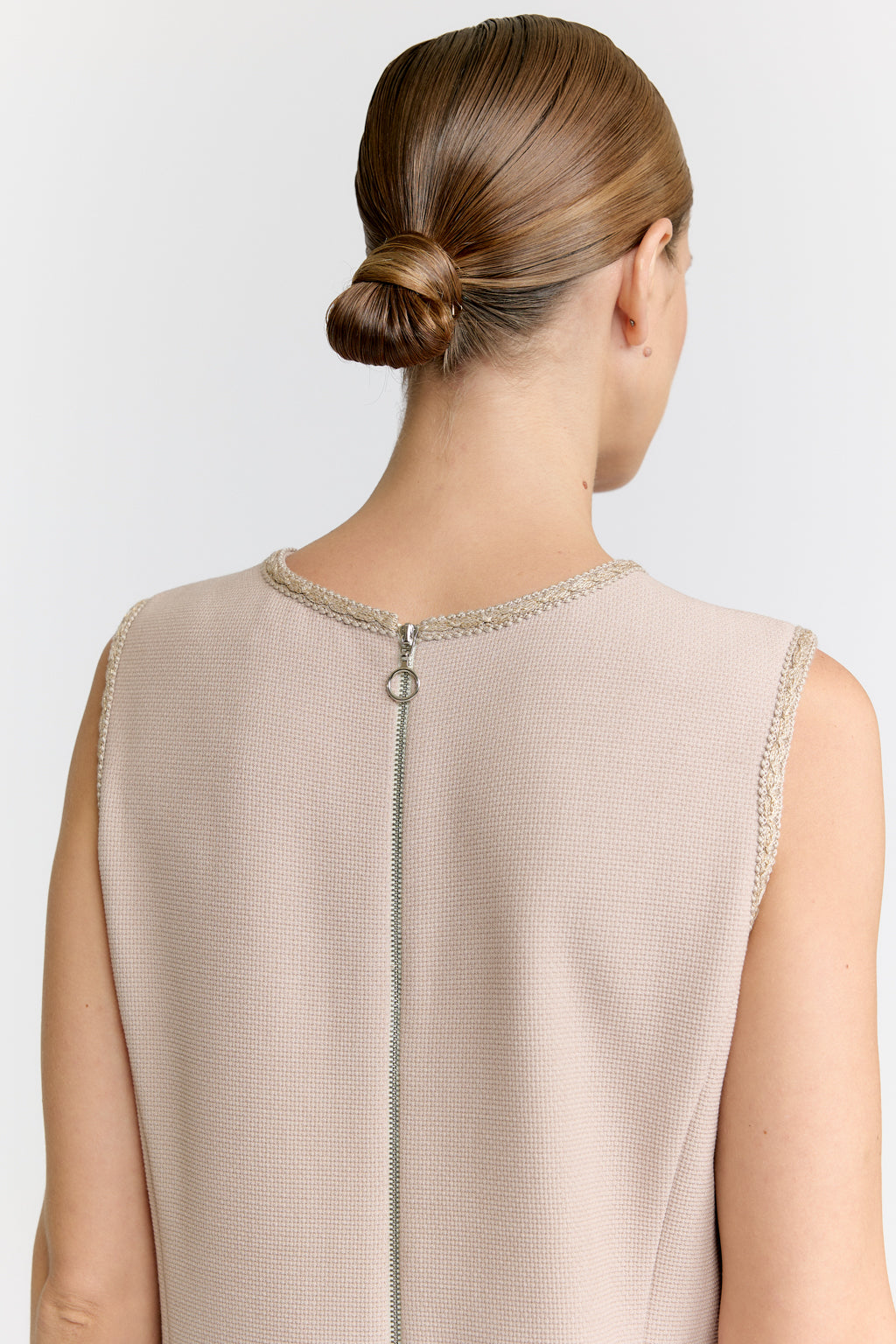 Beige sleeveless top with a chain detail on a plain background