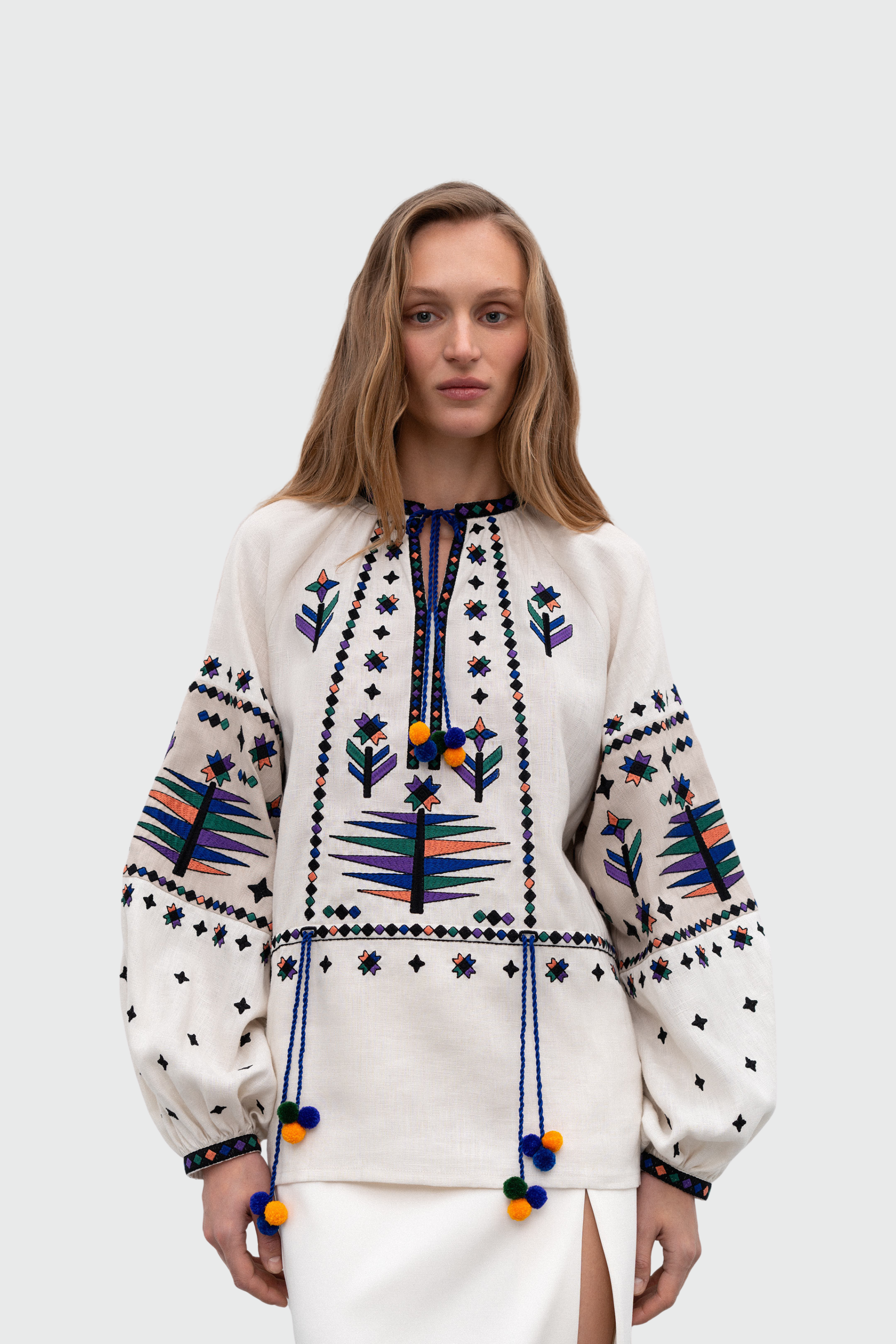 Beautiful Woman wearing a white blouse with colorful embroidery on a plain background
