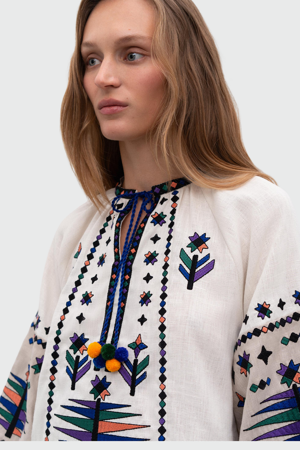 Woman wearing a white blouse with colorful embroidery on a white background south american fashion