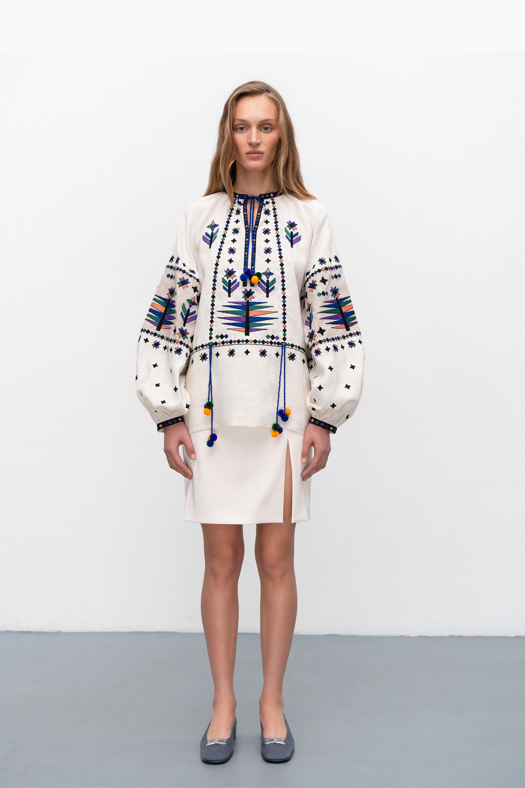 Woman wearing a traditional embroidered blouse with a plain background