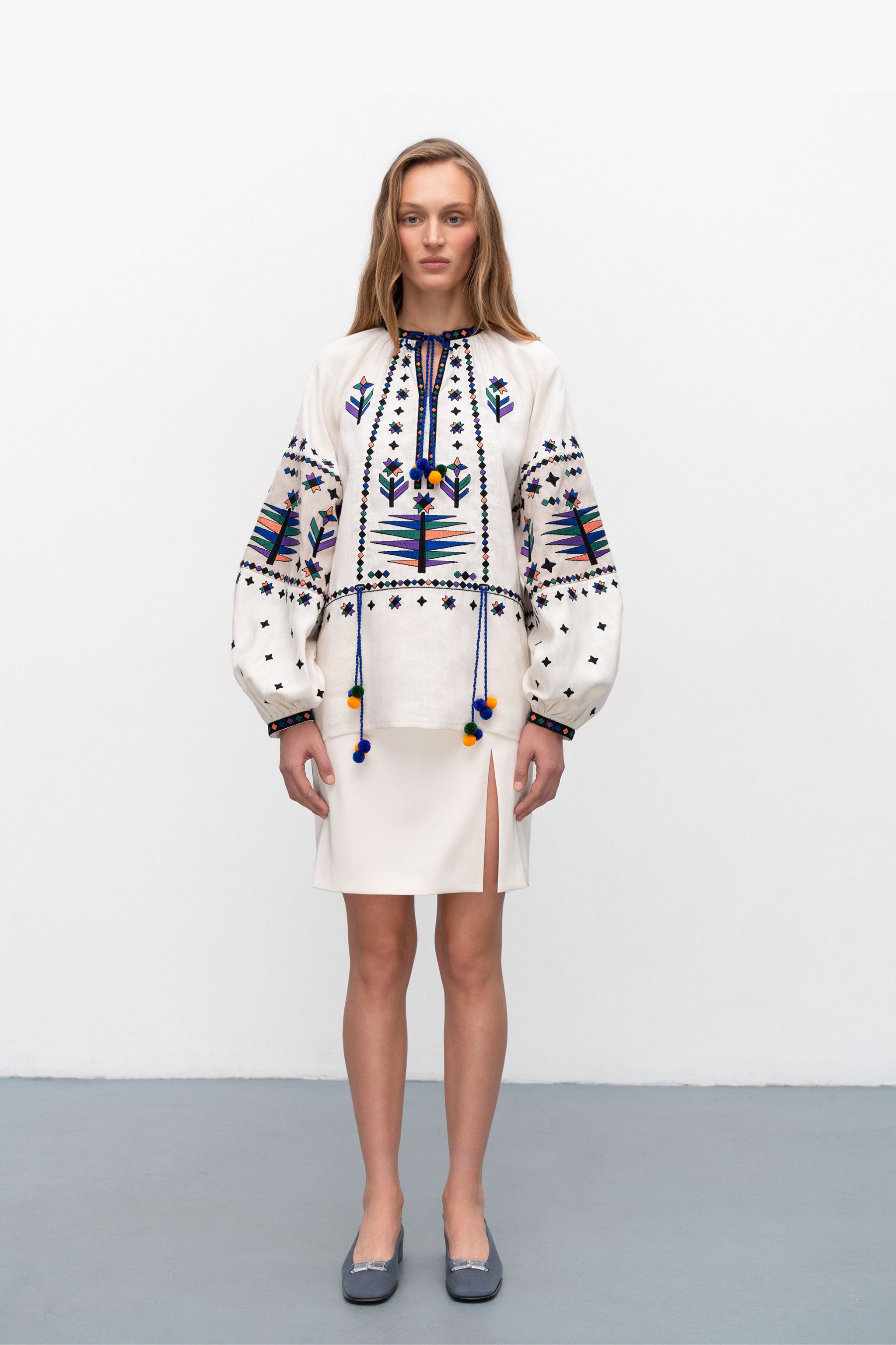 Woman wearing a traditional embroidered blouse with a plain background