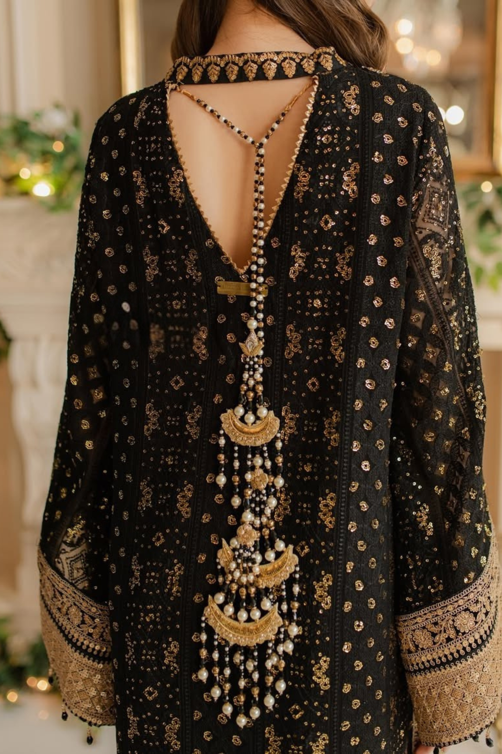 Black embroidered dress with gold detailing and a long necklace.