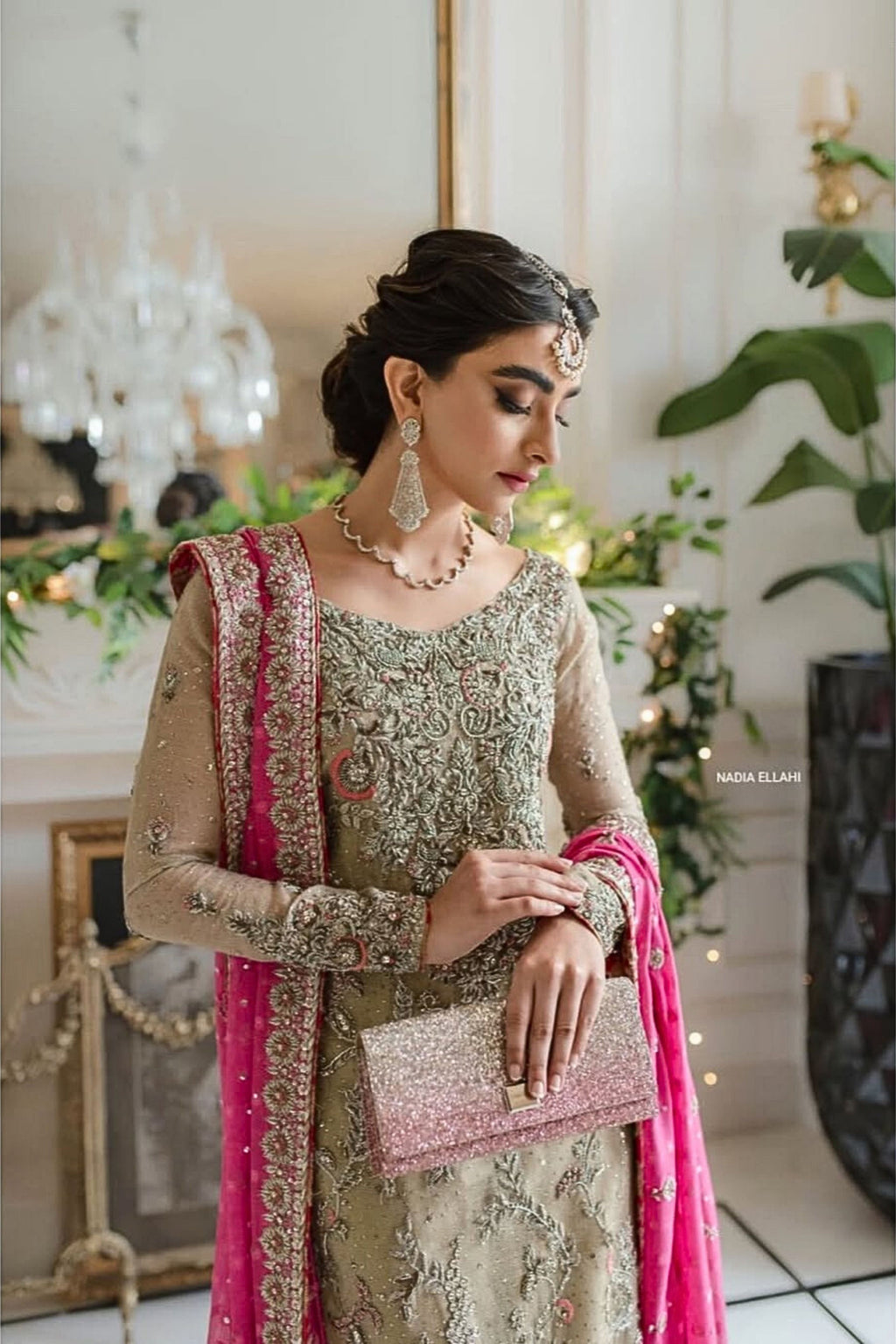 Woman in traditional attire with pink and gold details in a decorated indoor setting