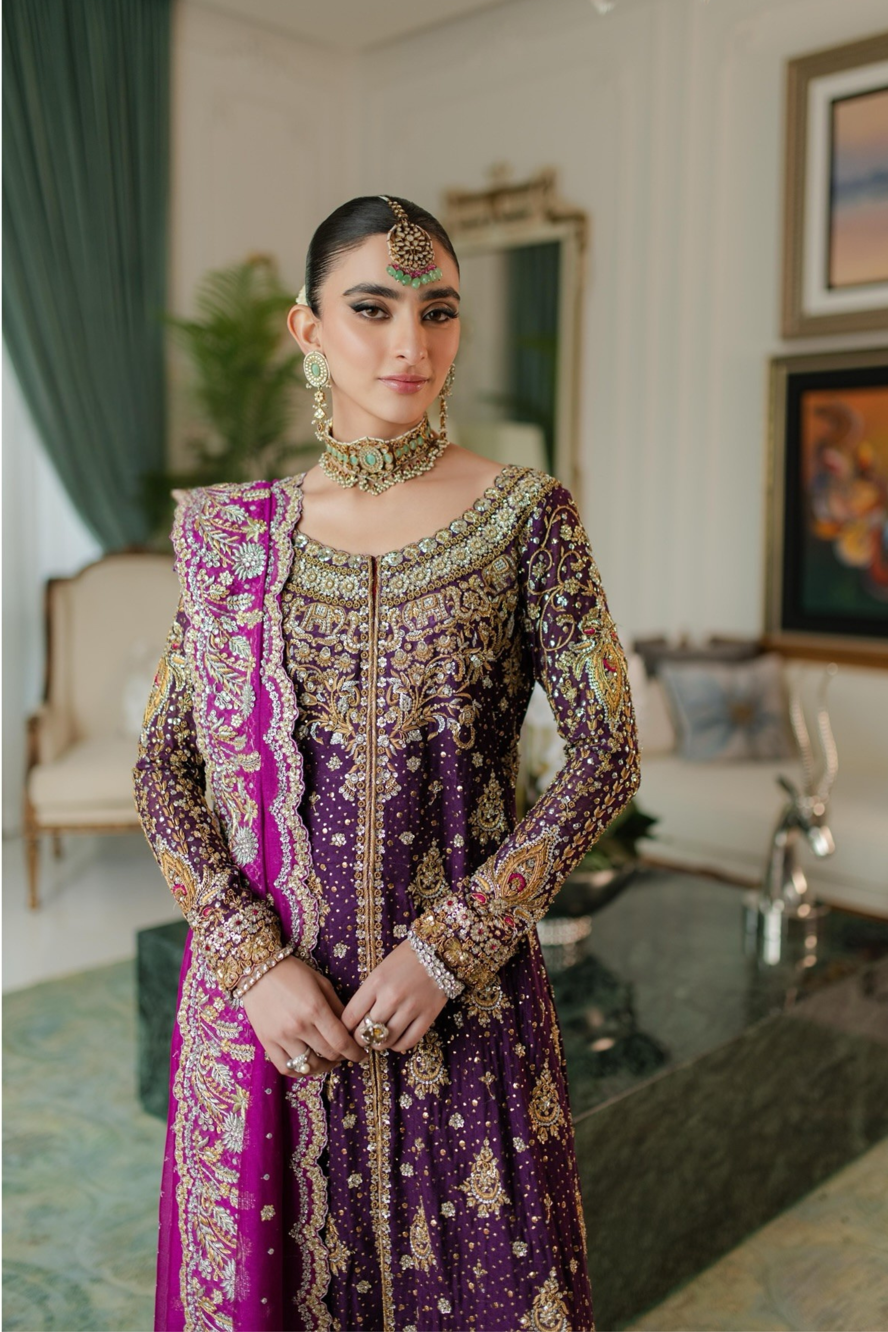 Woman in a purple and gold traditional outfit in an elegant room.