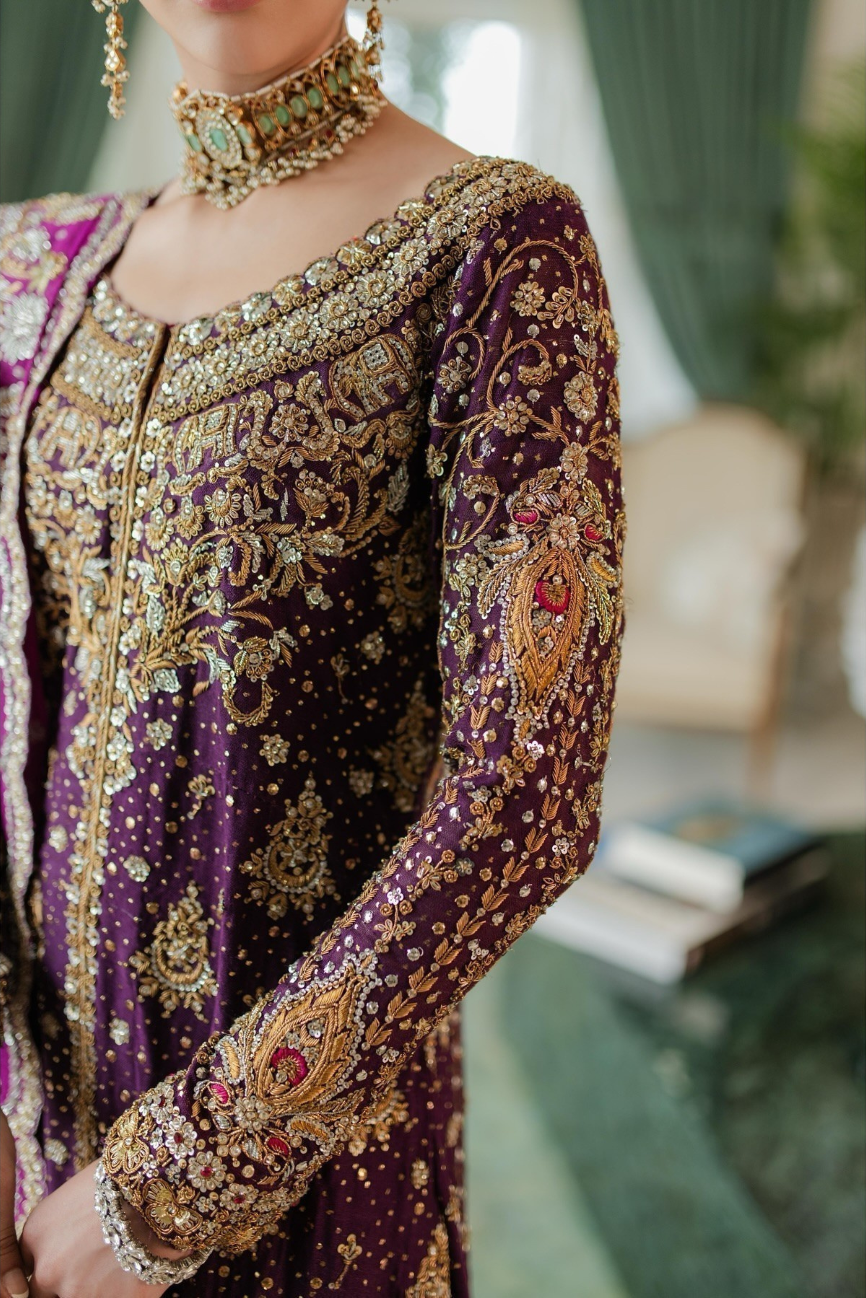 Close-up of a person wearing a purple and gold embroidered traditional outfit.