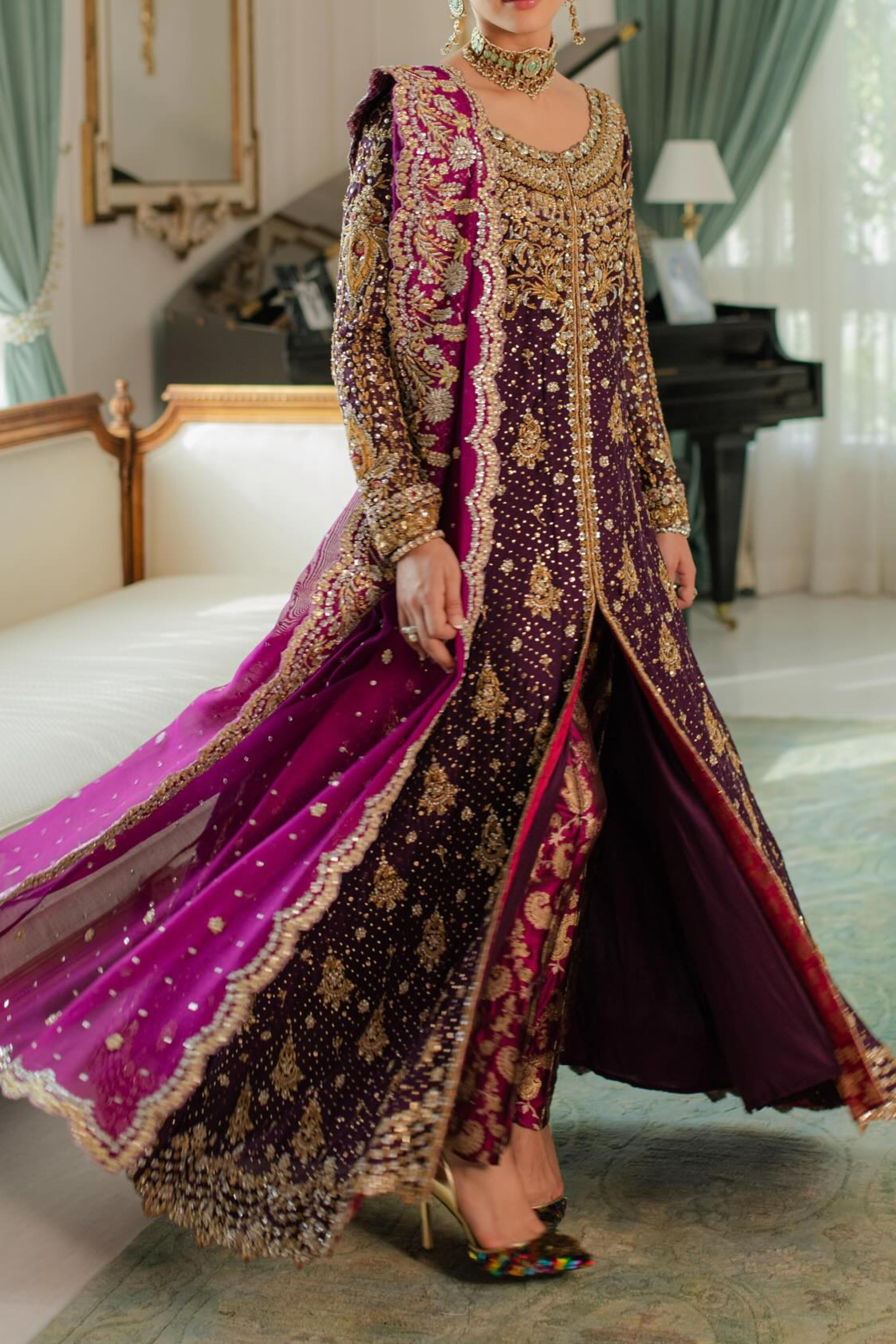 Woman in a traditional embroidered outfit with magenta accents in an elegant room.