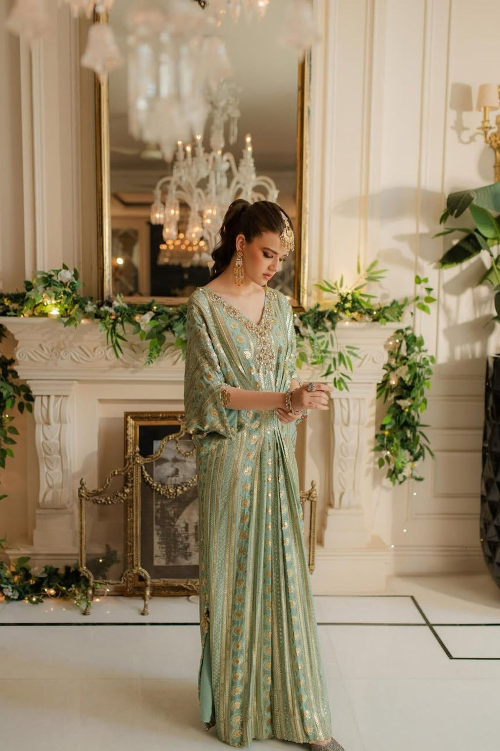 Woman in a green dress standing in an elegant room with decorative elements.