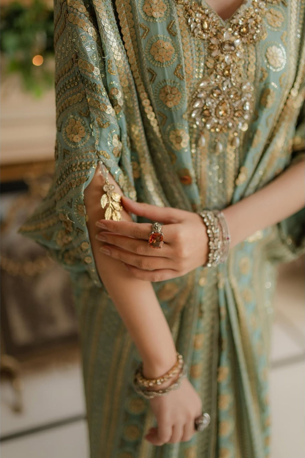 Close-up of a person wearing a green embroidered outfit with gold details.