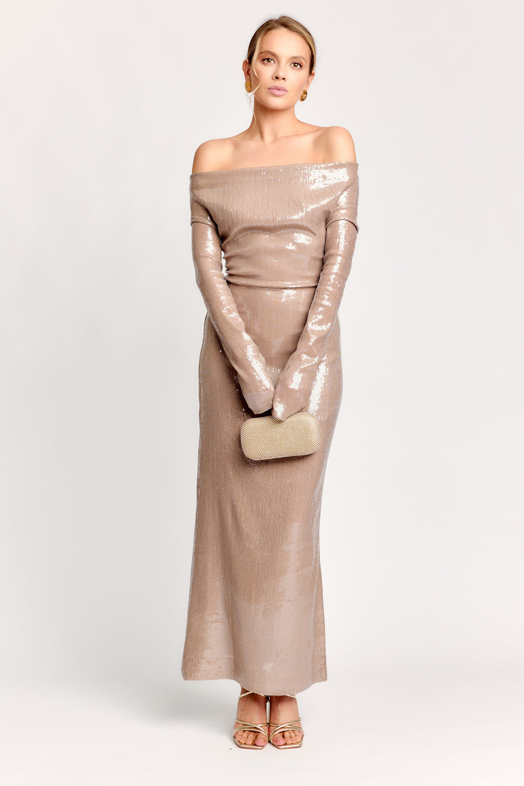 Woman wearing a beige off-shoulder dress with matching clutch on a white background