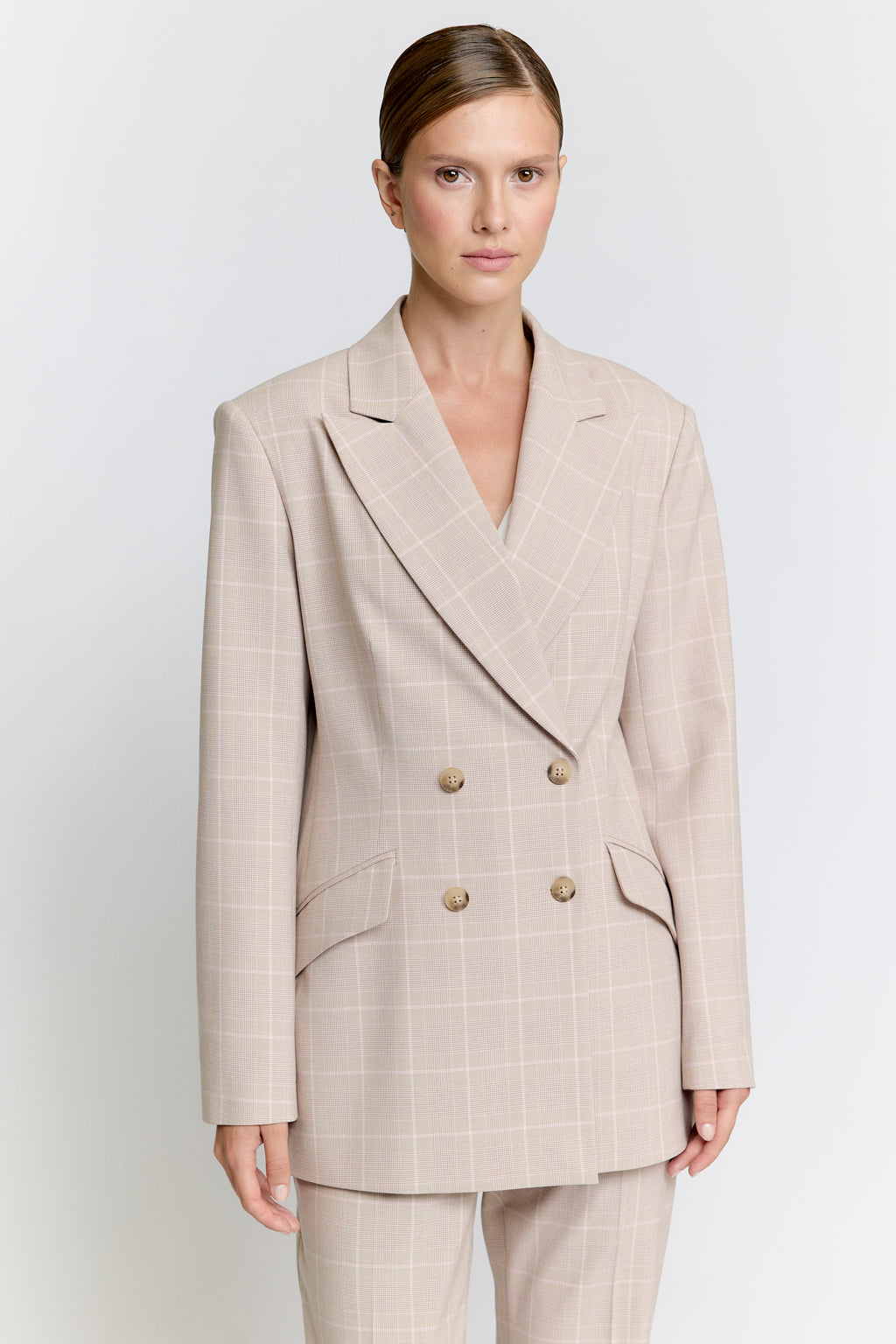 Woman wearing a beige suit on a white background Luxury Women's Wear | Custom-Made, Eco-Friendly Fashion