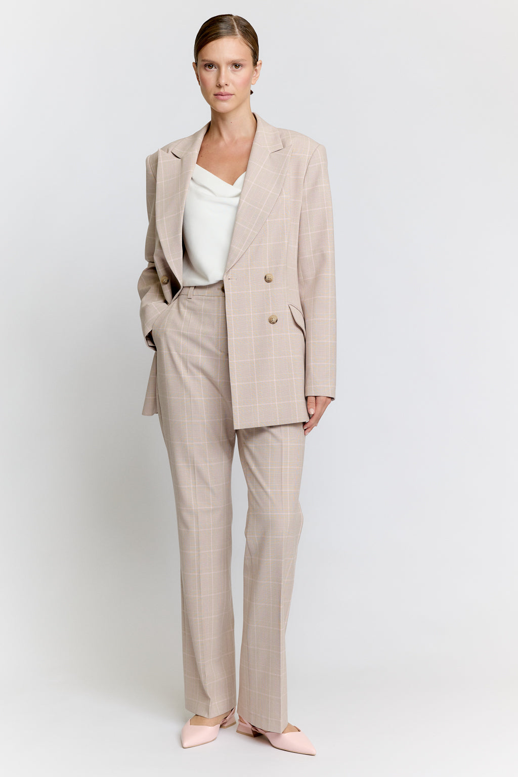 Woman wearing a beige suit on a white background Luxury Women's Wear | Custom-Made, Eco-Friendly Fashion