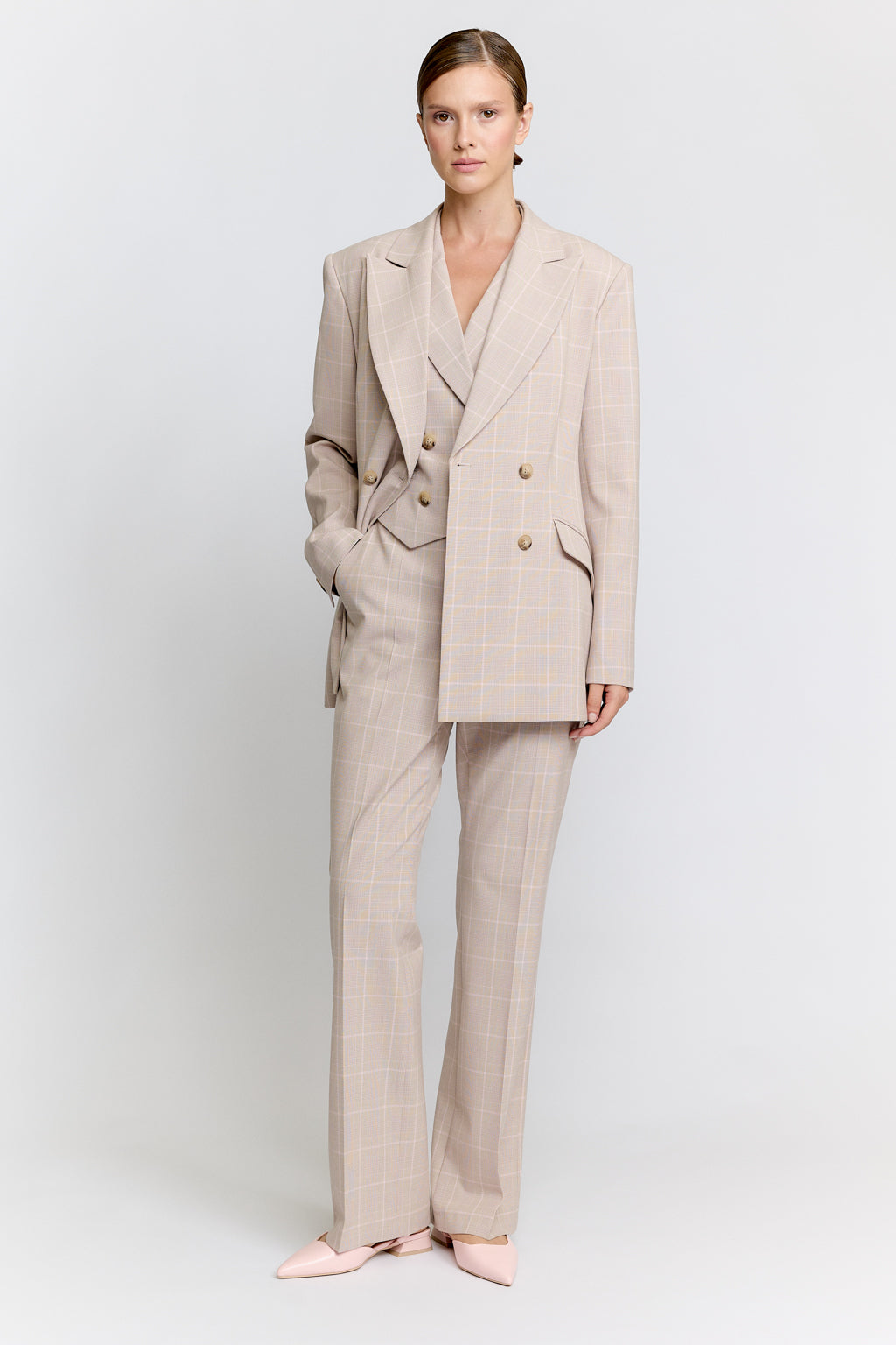 Woman wearing a beige suit on a white background Luxury Women's Wear | Custom-Made, Eco-Friendly Fashion