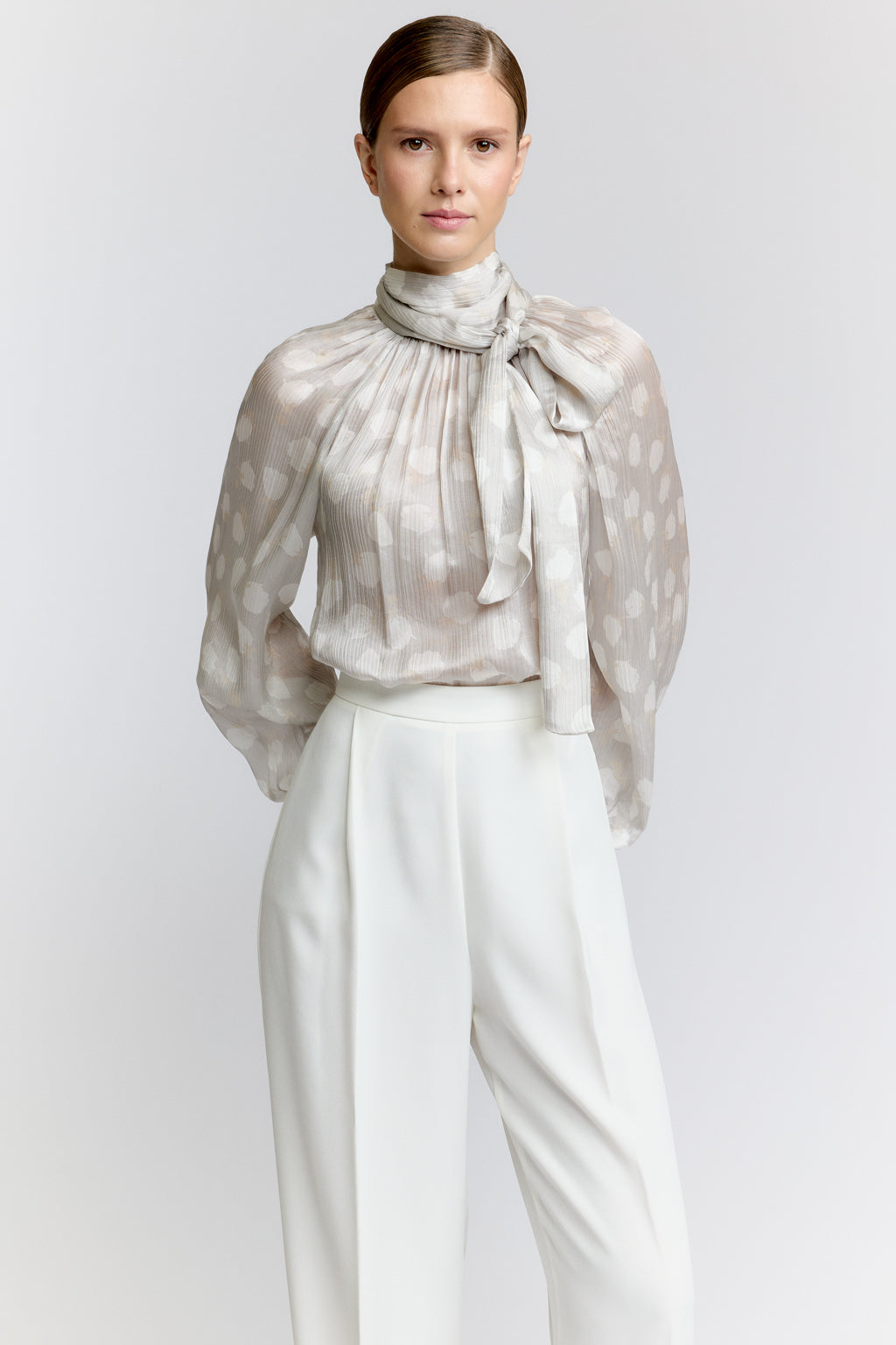 Woman wearing a sheer polka dot blouse with a white background