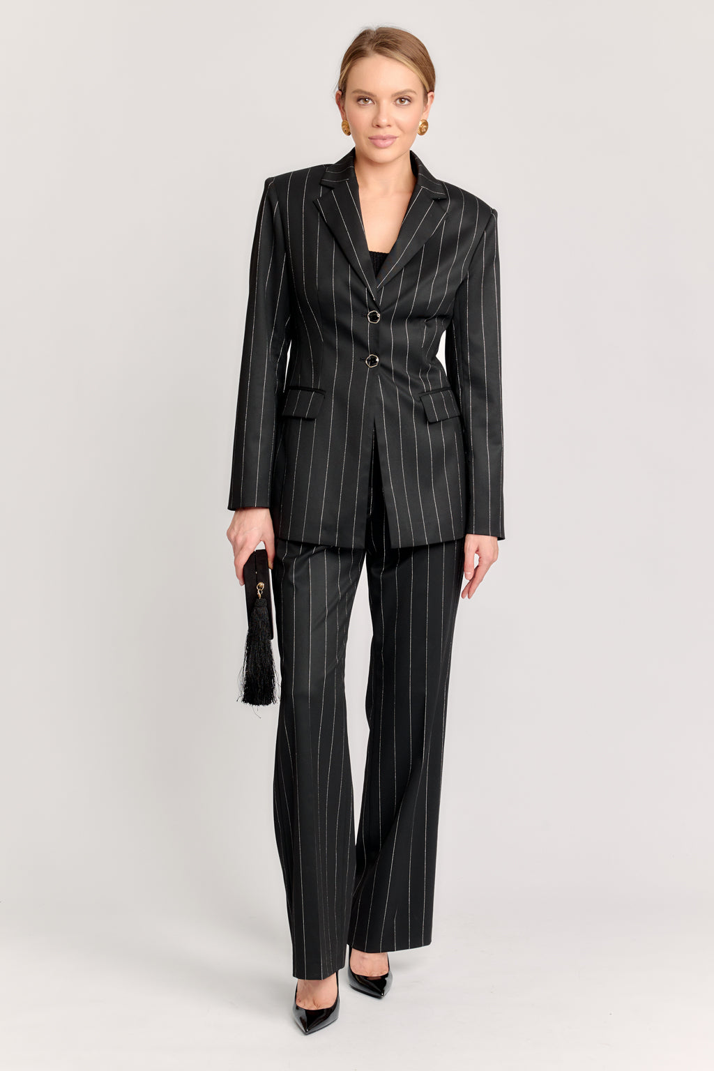 Woman wearing a black pinstripe suit on a light gray background