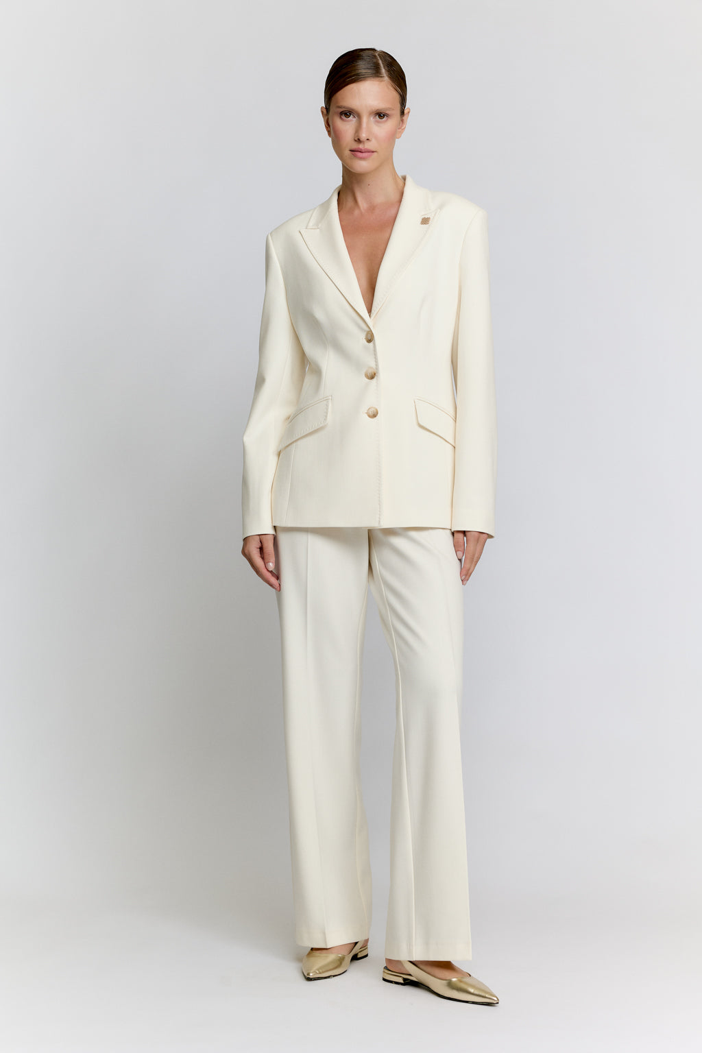 Woman wearing a white suit on a plain background