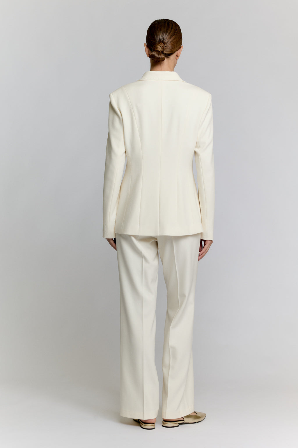 Person wearing a white suit standing against a plain background