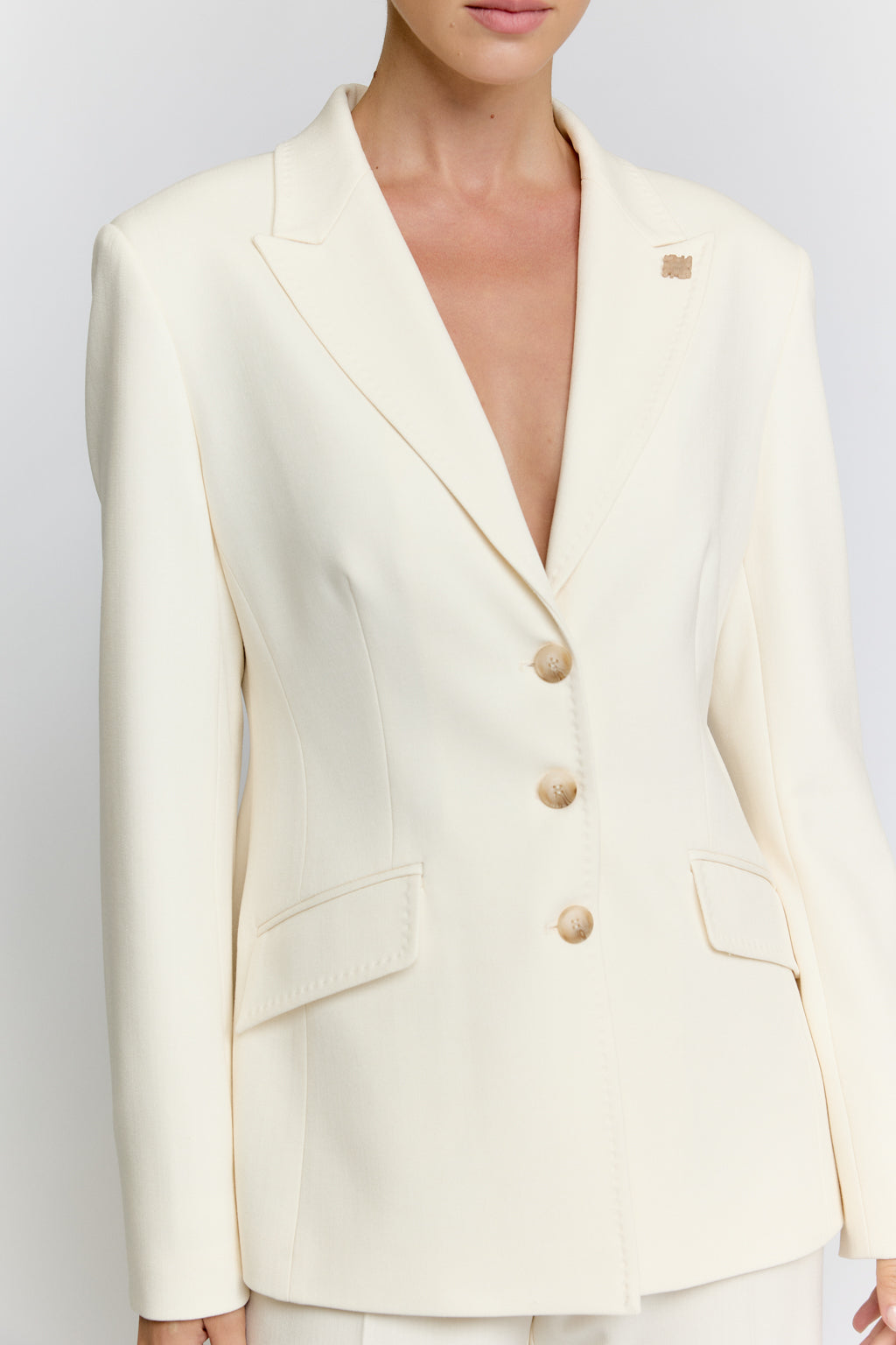 White blazer worn by a person on a plain background