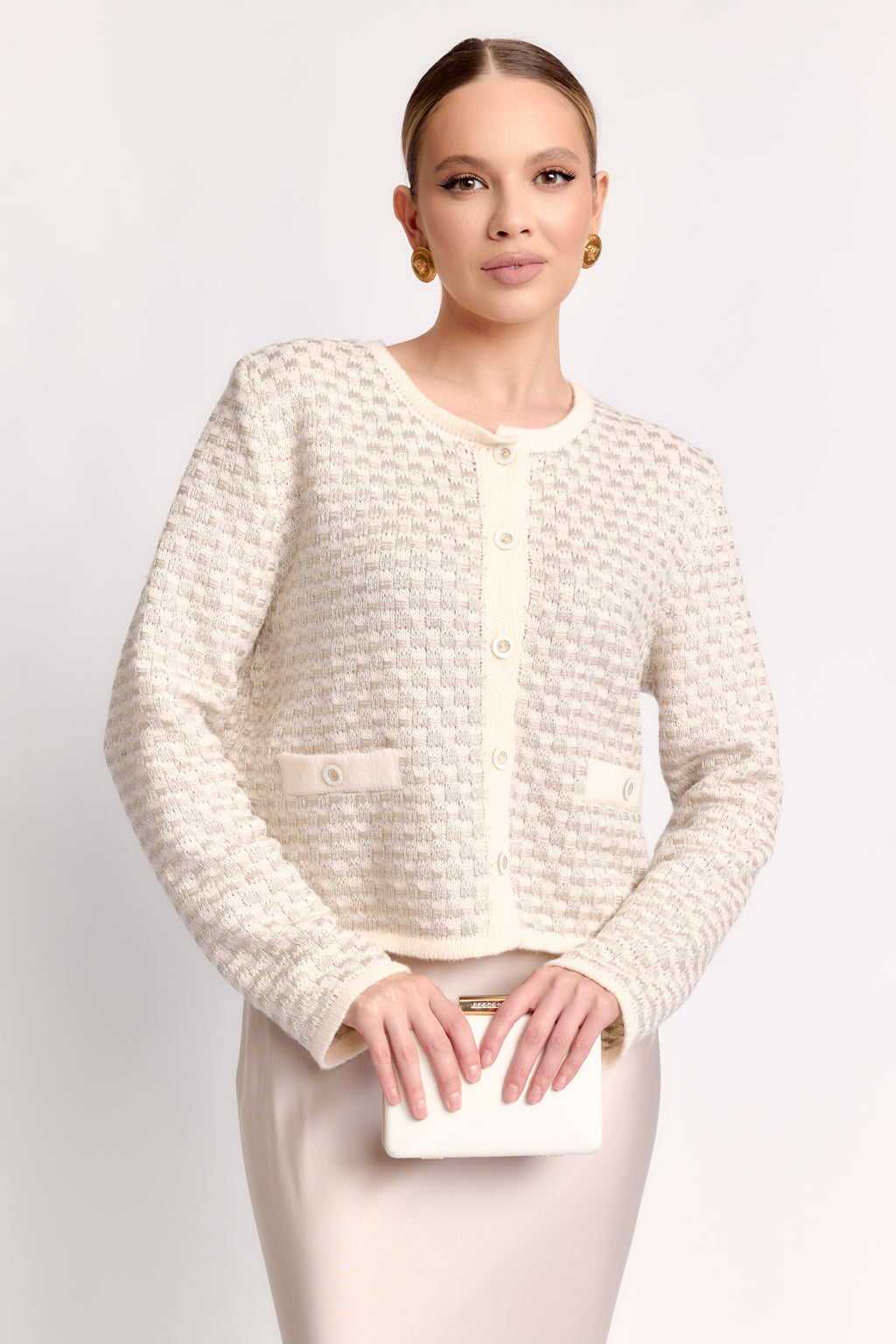 Woman wearing a textured white cardigan on a plain background