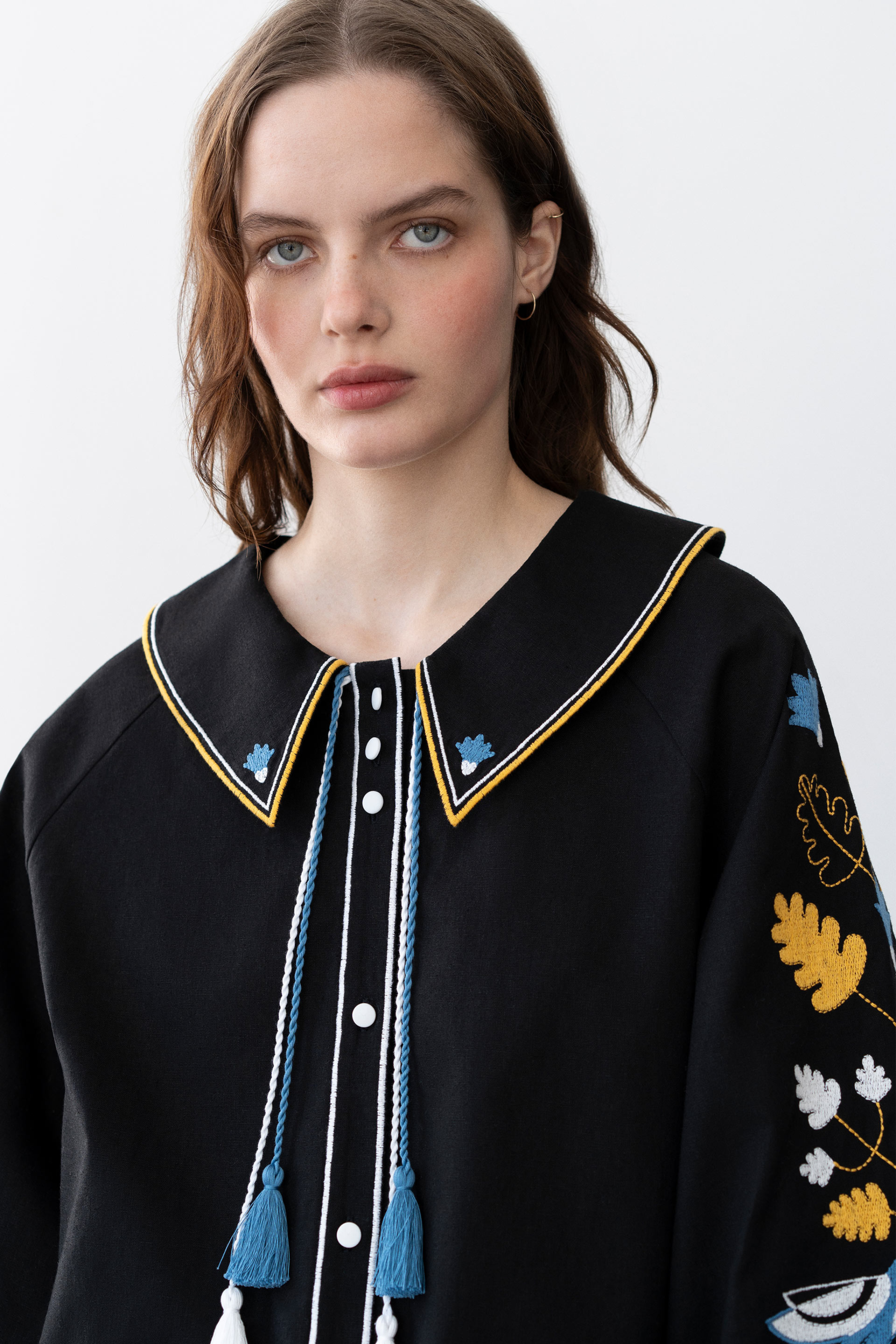 Woman wearing a black embroidered jacket with colorful details on a white background