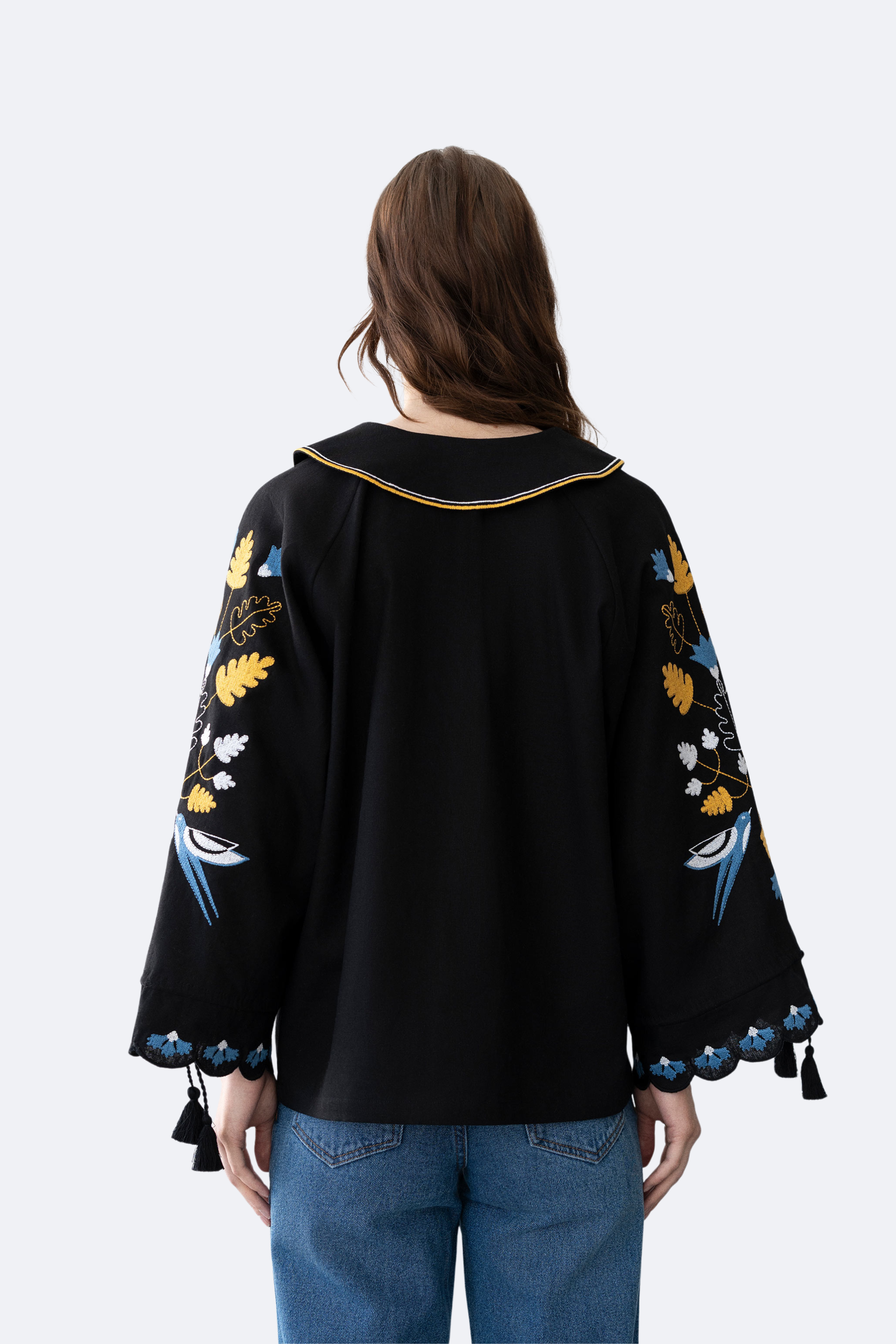 Black embroidered blouse worn by a person on a white background