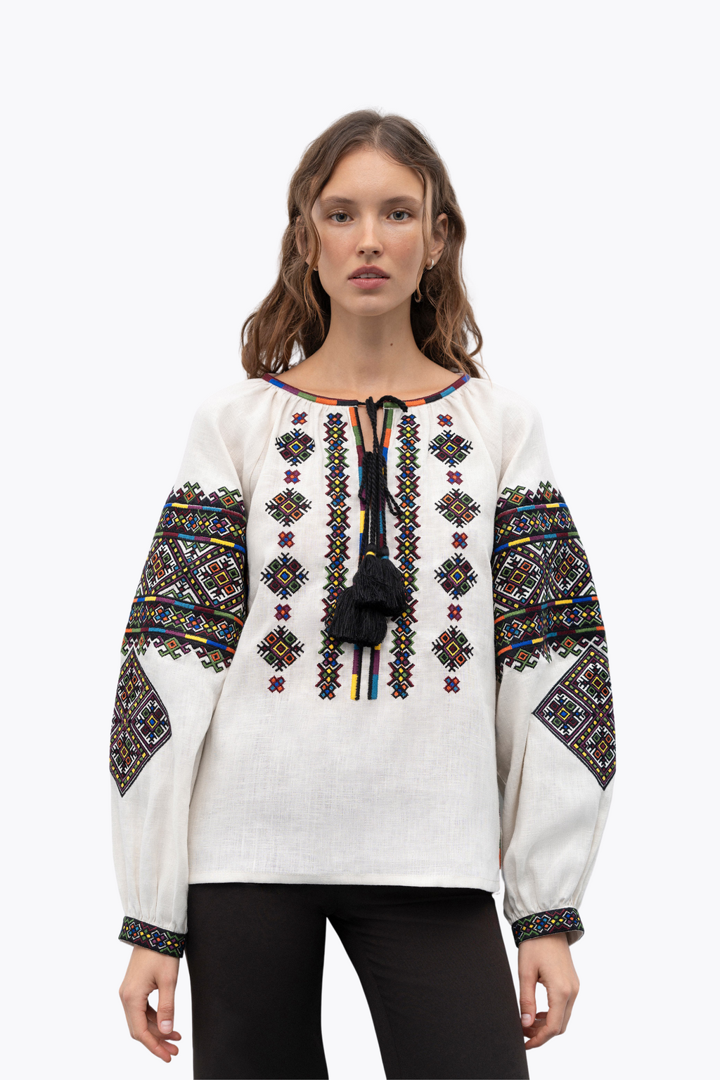 Woman wearing a white blouse with colorful embroidery on a white background