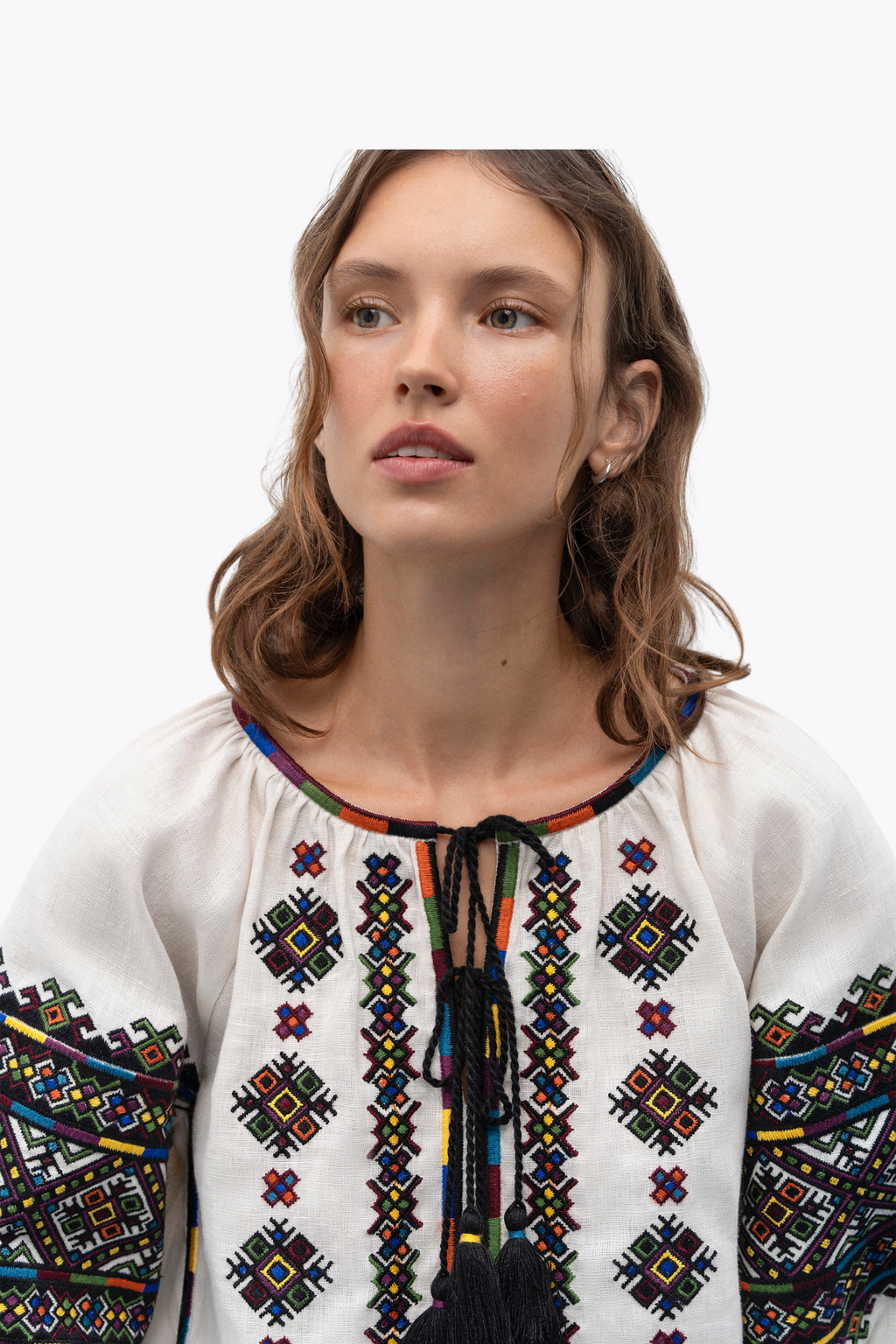 Woman wearing a white blouse with colorful embroidery on a white background