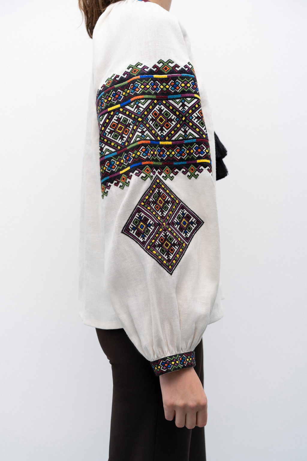White blouse with colorful geometric embroidery on a white background
