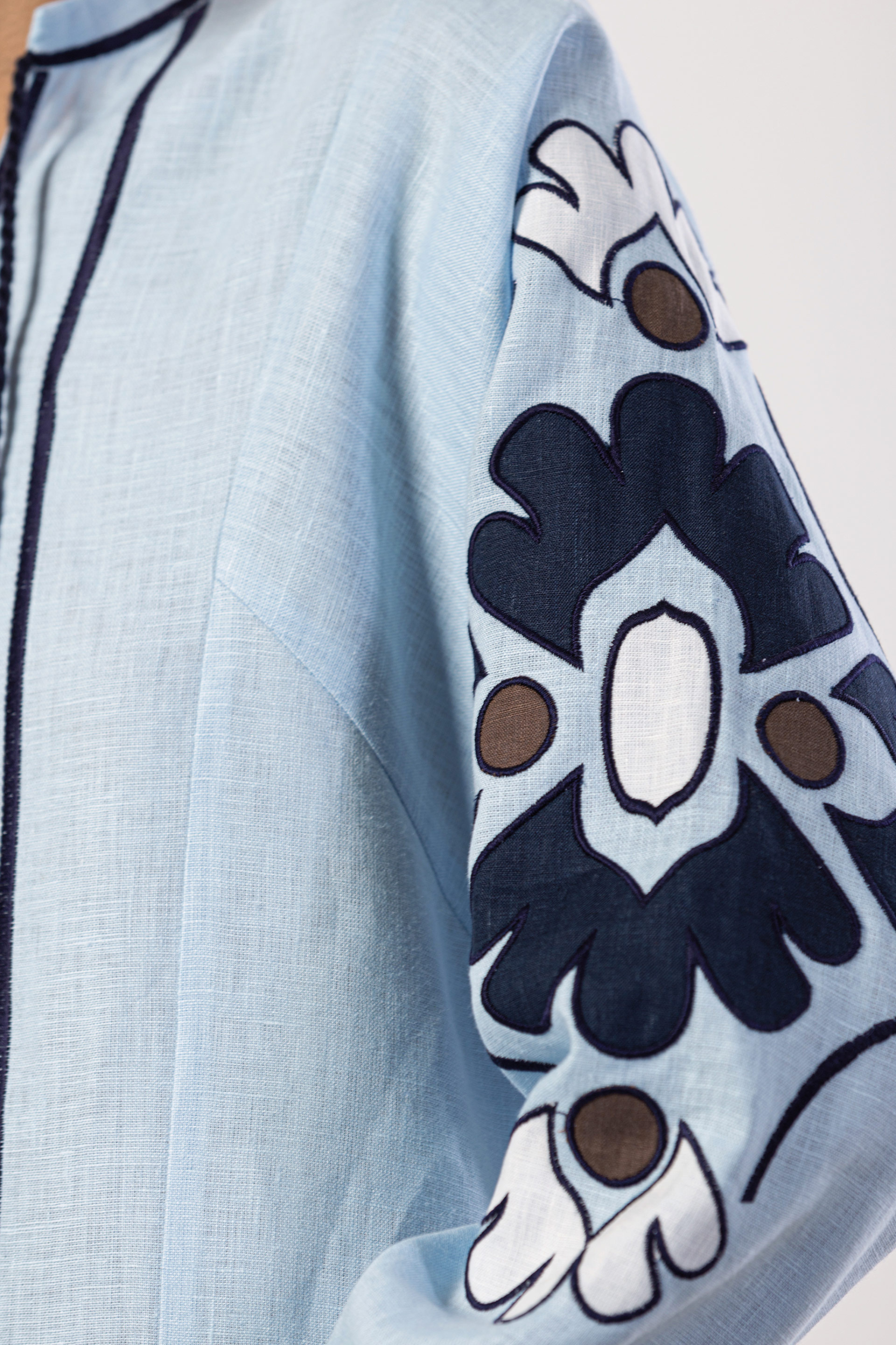Light blue garment with a decorative sleeve featuring black, white, and brown patterns.