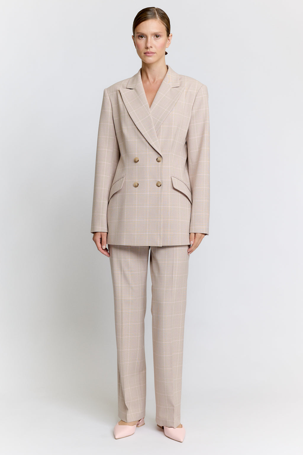 Woman wearing a beige suit on a white background Luxury Women's Wear | Custom-Made, Eco-Friendly Fashion