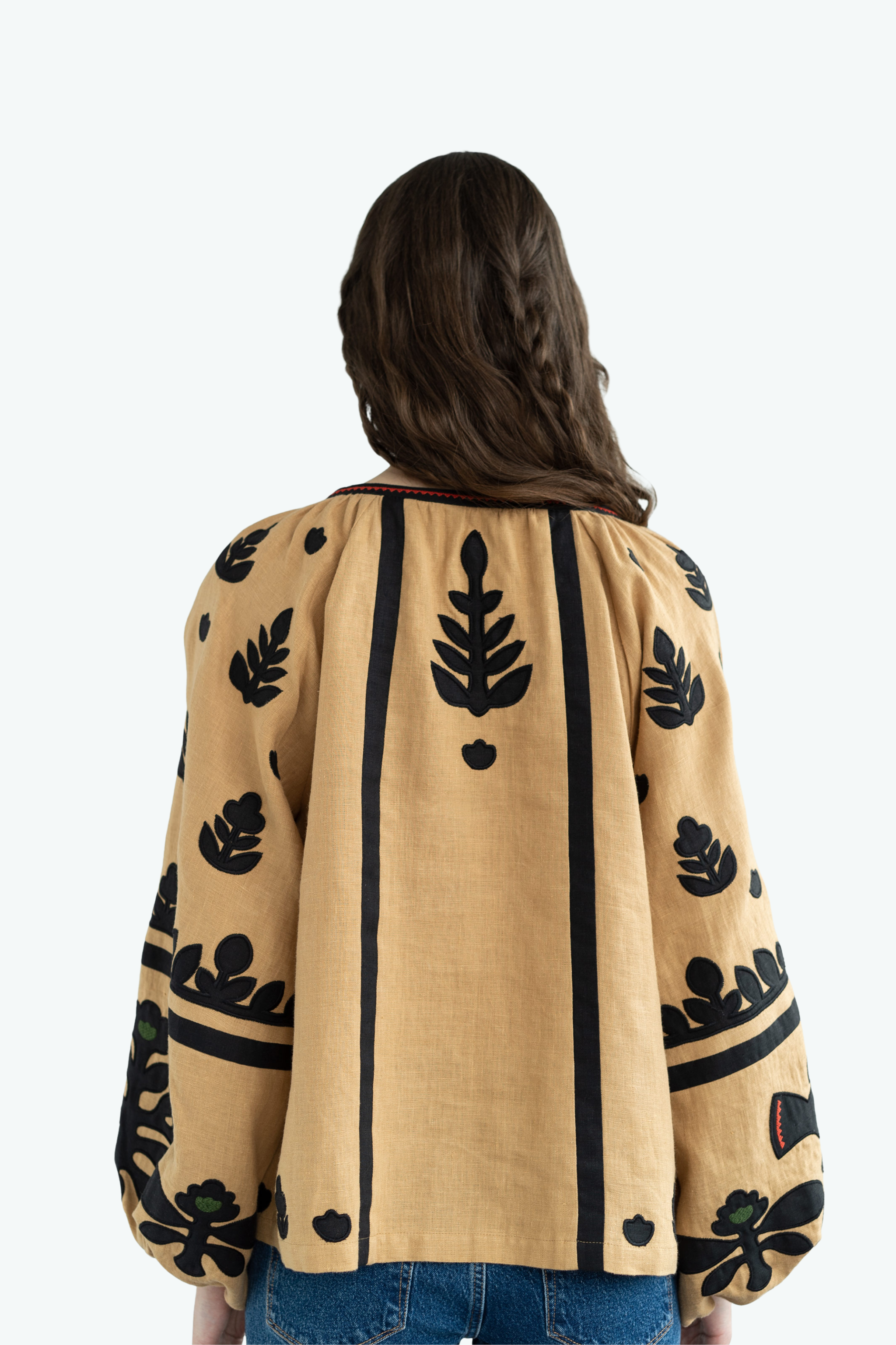 Woman wearing a beige jacket with black leaf patterns on a white background