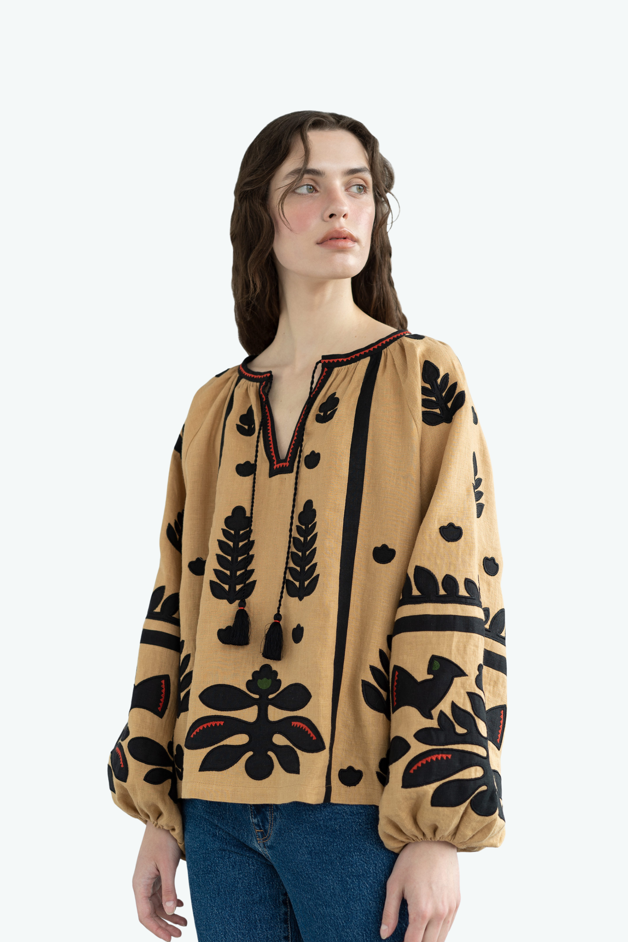 Woman wearing a beige blouse with black floral patterns on a white background